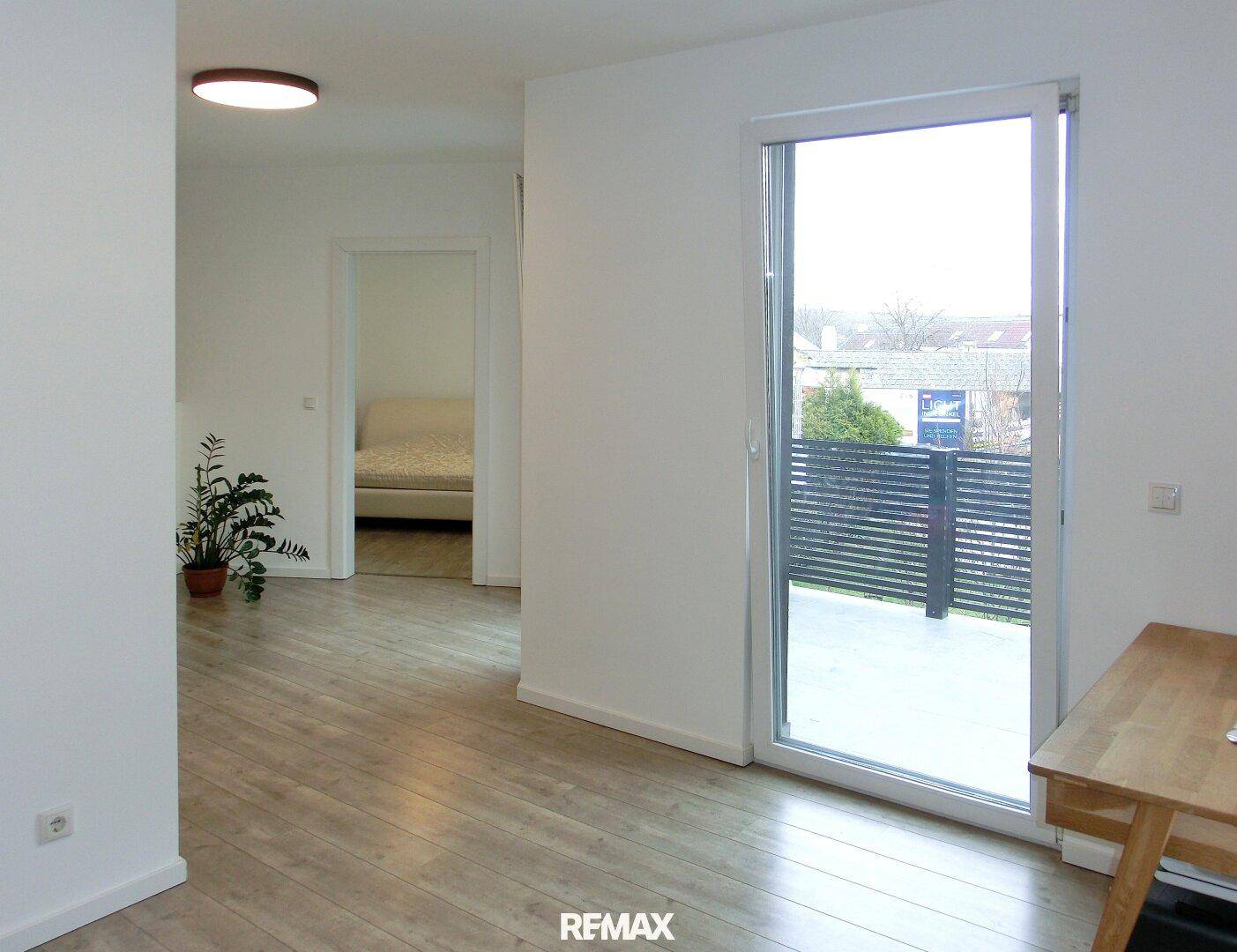 Heller Flur mit Laminatboden und Zugang zu einem Balkon.