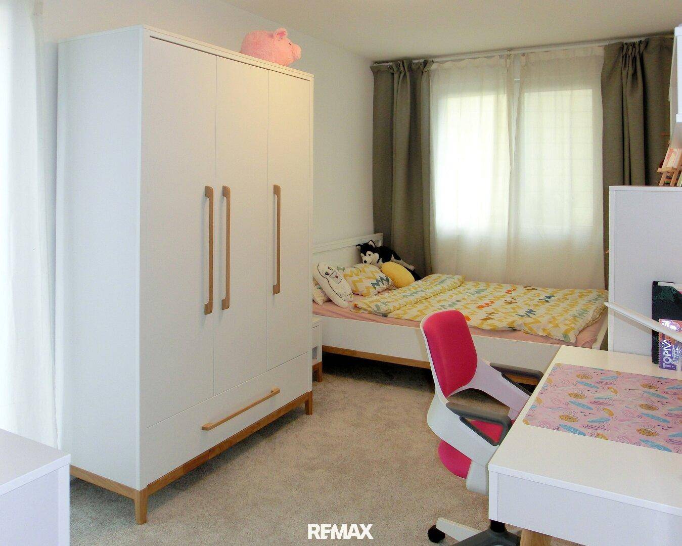Kinderzimmer mit weißem Kleiderschrank, Bett und Schreibtisch.