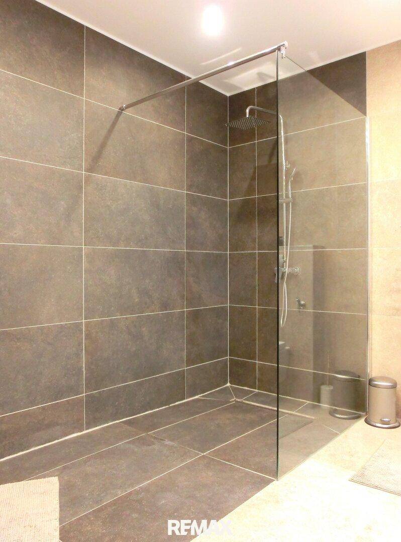 Geräumige begehbare Dusche mit Glasabtrennung und Regenduschkopf.
