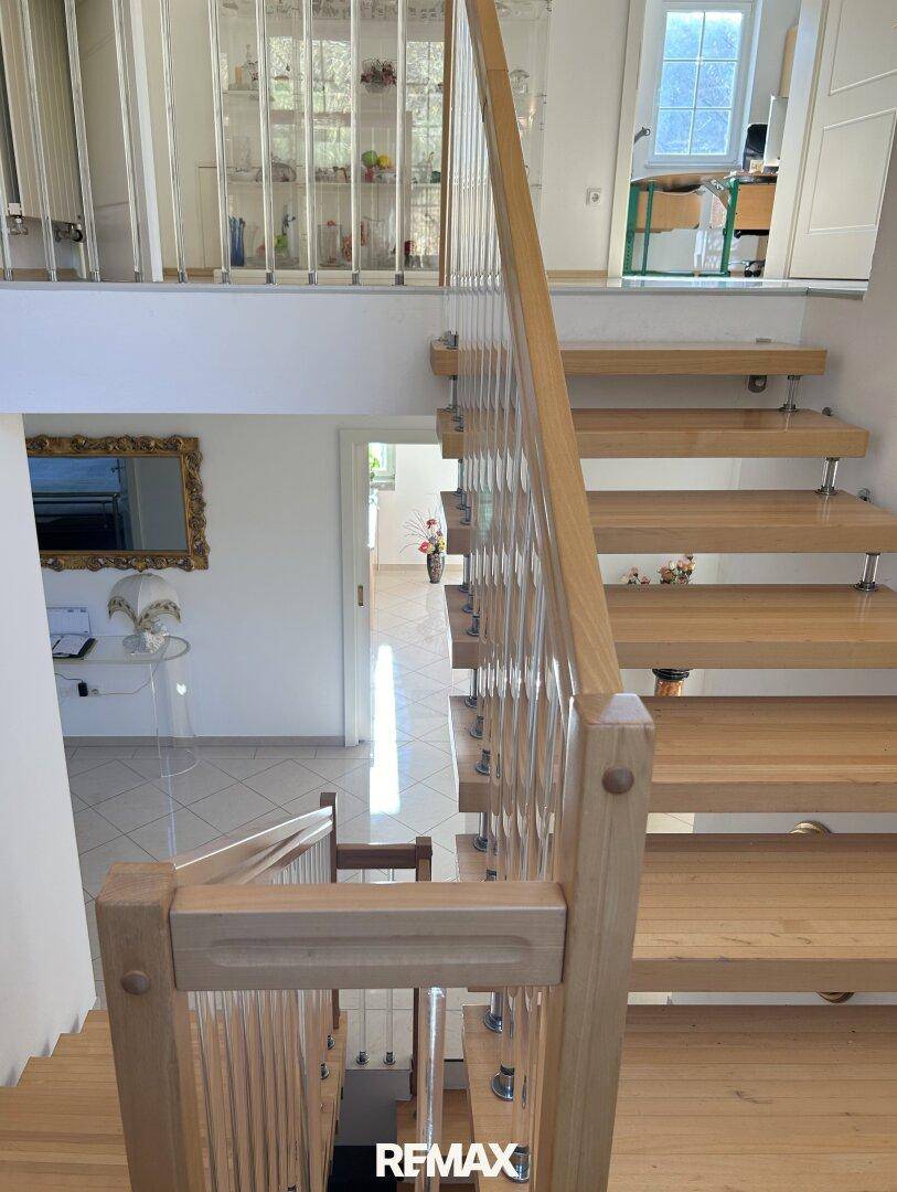 Moderne Holztreppe mit offenen Stufen und elegantem Geländer, führt in die obere Etage.