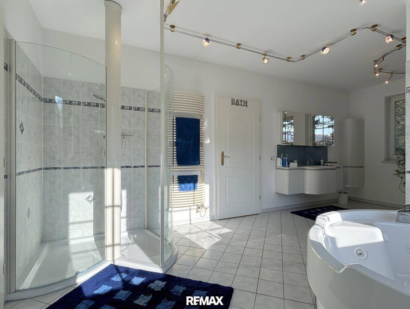 Großes Badezimmer mit Eckdusche, Whirlpool, Doppelwaschbecken und moderner Beleuchtung.