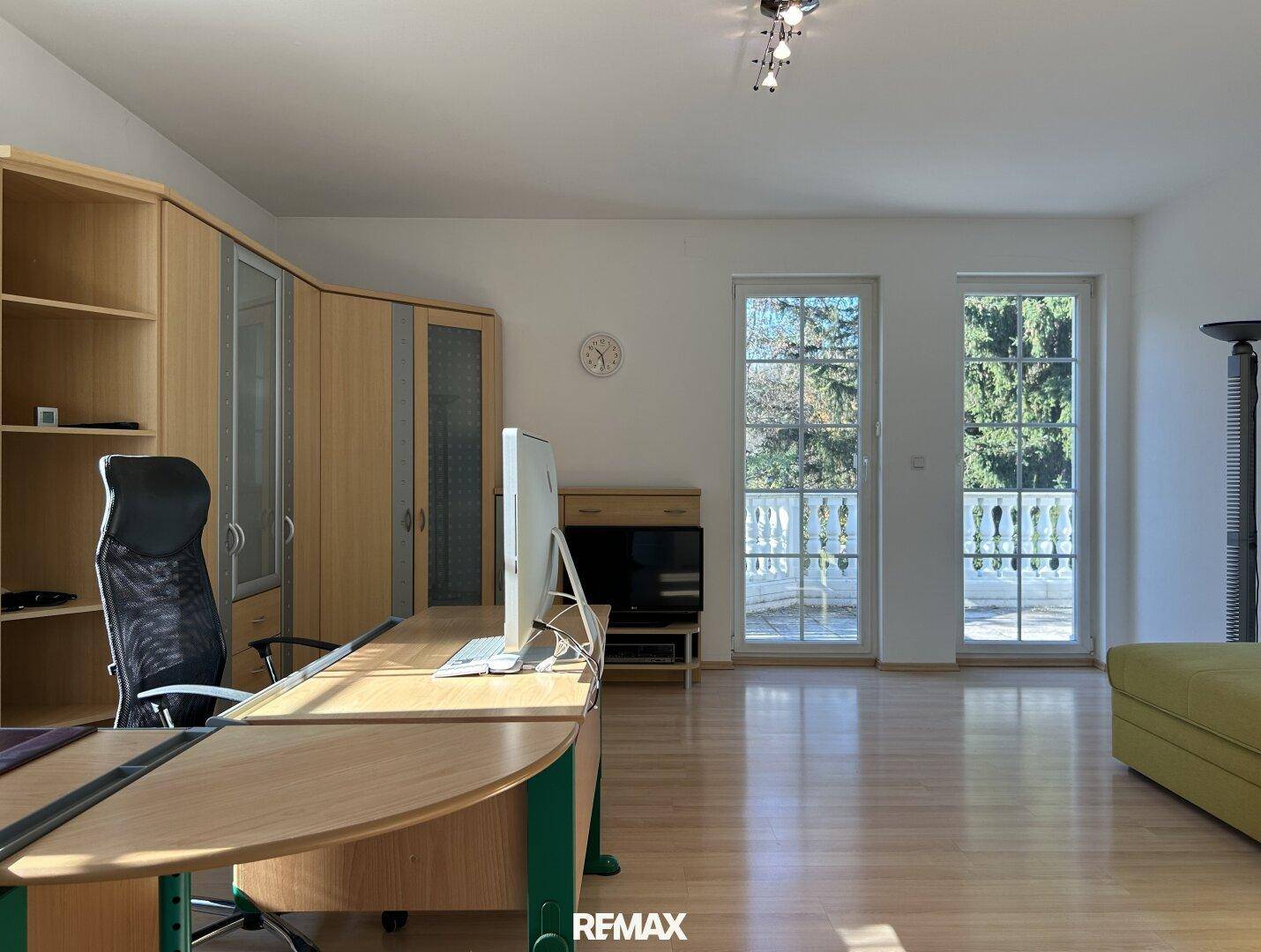Geräumiges Arbeitszimmer mit Laminatboden, großen Fenstern und Blick ins Grüne.