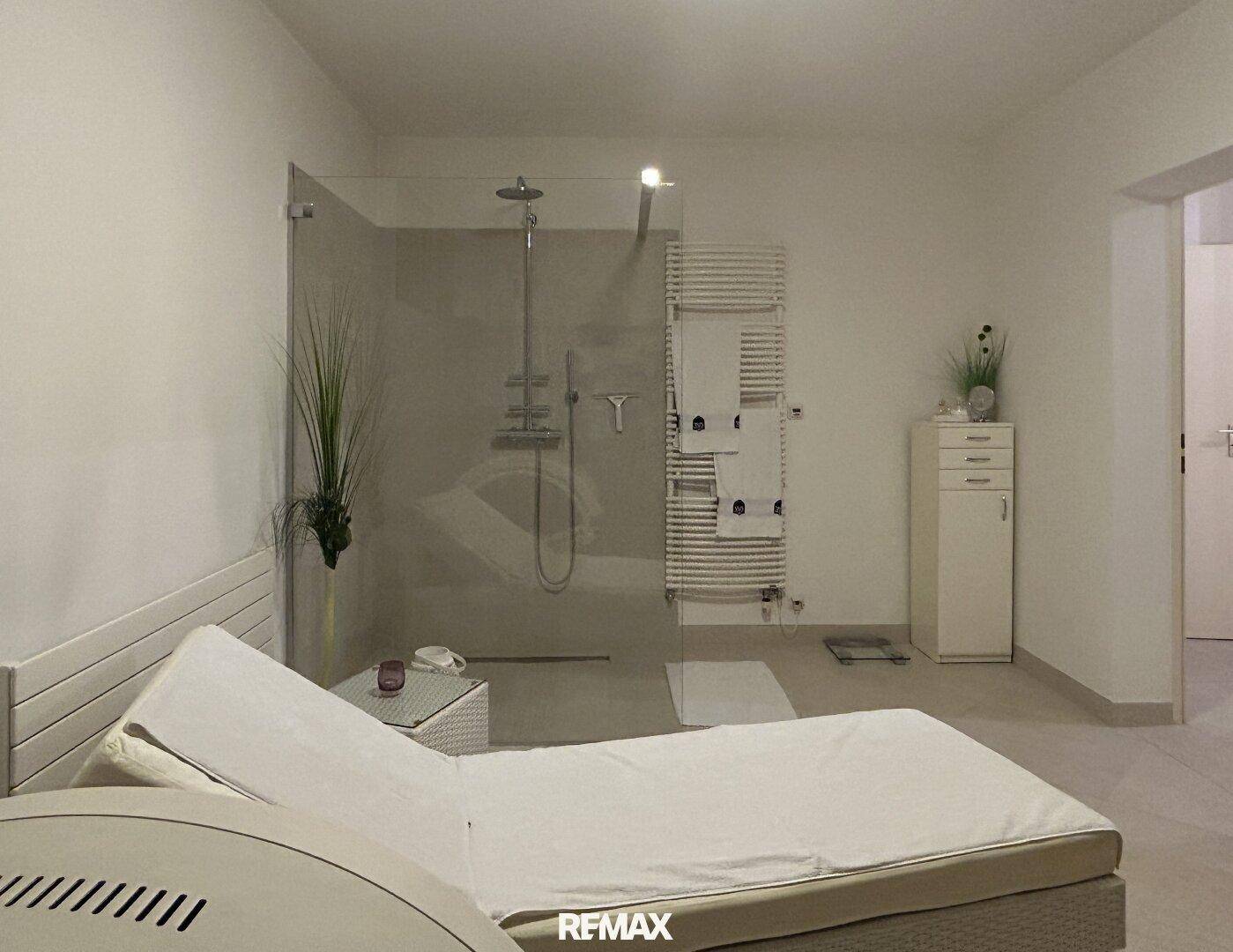 Moderner Wellnessbereich mit großer Dusche, beheiztem Handtuchhalter und Liegefläche.
