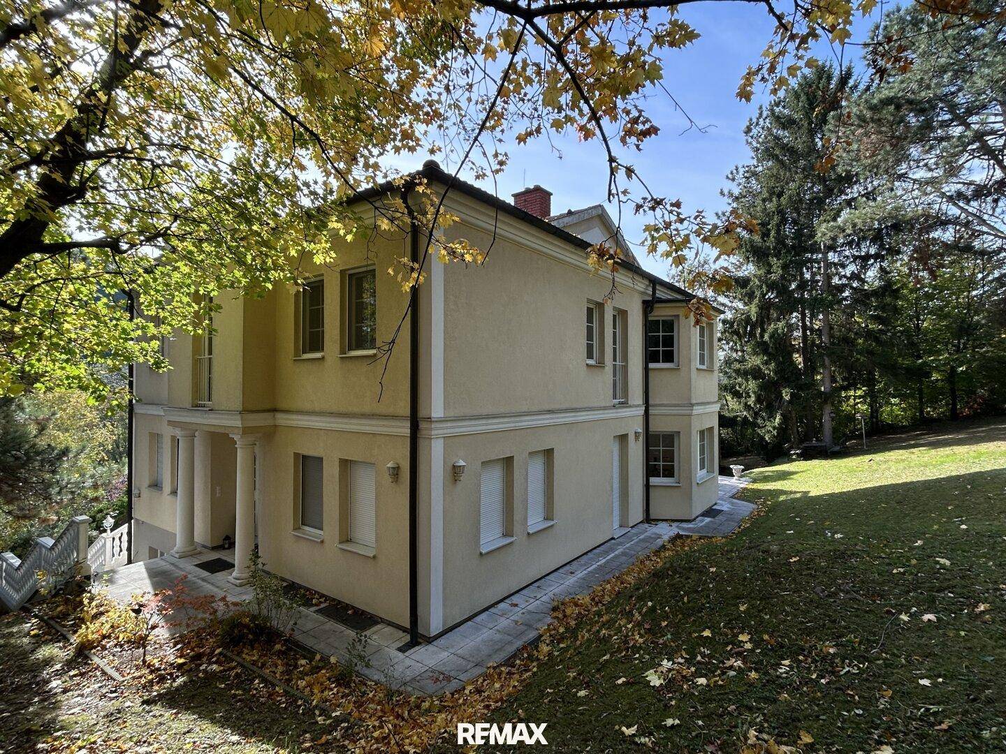 Elegantes Haus mit klassischer Architektur, umgeben von einem großen Garten und Bäumen.
