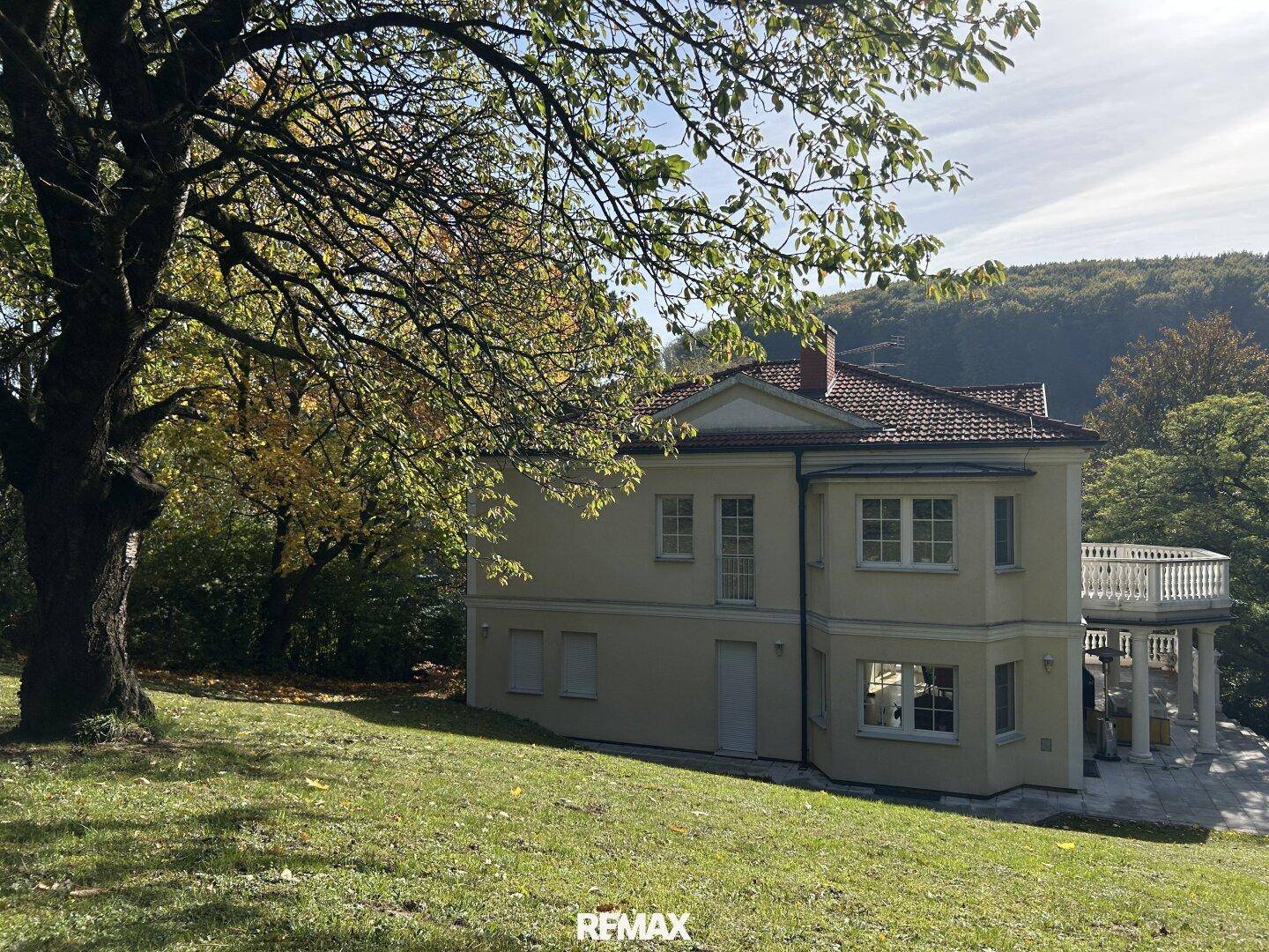 Charmantes Haus mit Balkon und weitläufigem Garten, eingebettet in grüne Hügellandschaft.