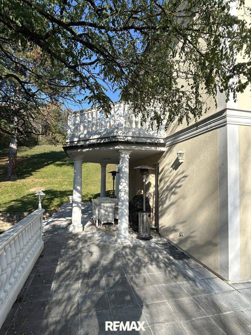 Überdachte Terrasse mit Säulen und Sitzgelegenheiten, ideal für entspannte Stunden im Freien.