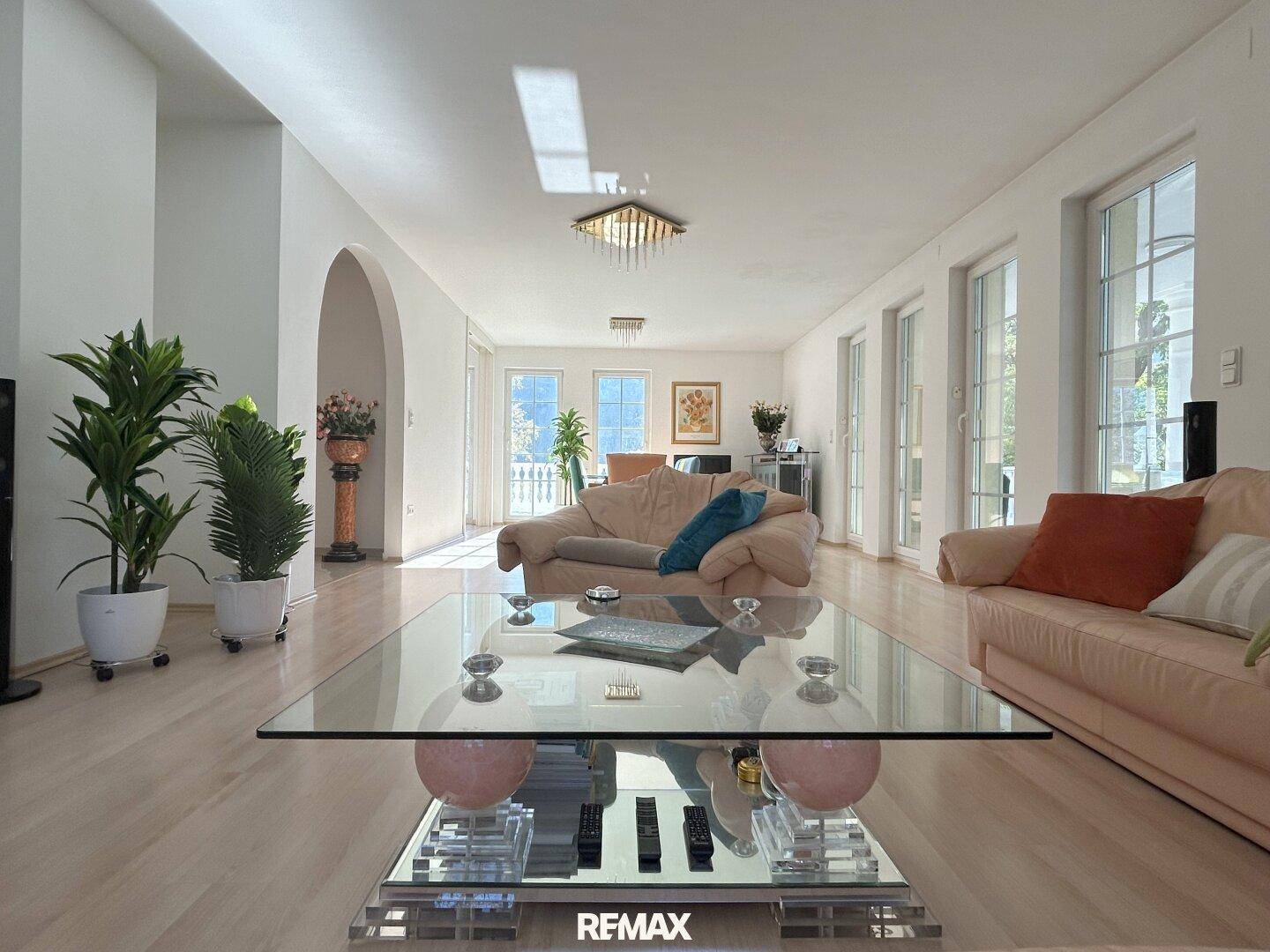 Helles Wohnzimmer mit elegantem Glastisch, bequemen Sofas und Zugang zur Terrasse.