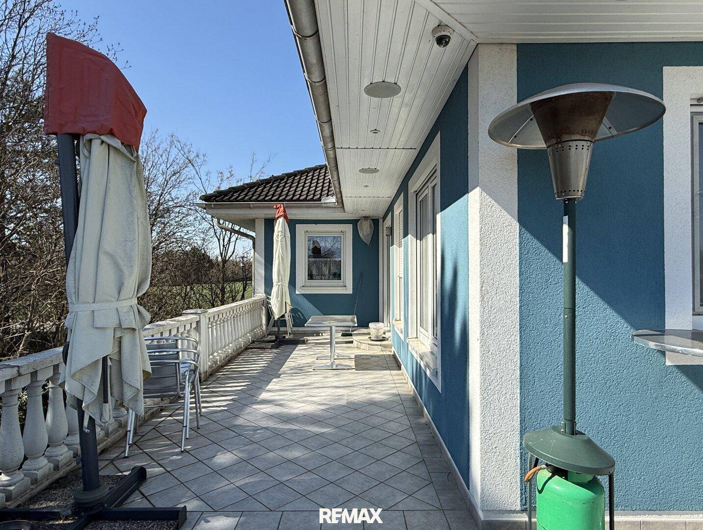 Gedeckte Terrasse mit Fliesenboden, Balustrade und Heizpilz für gemütliche Abende.