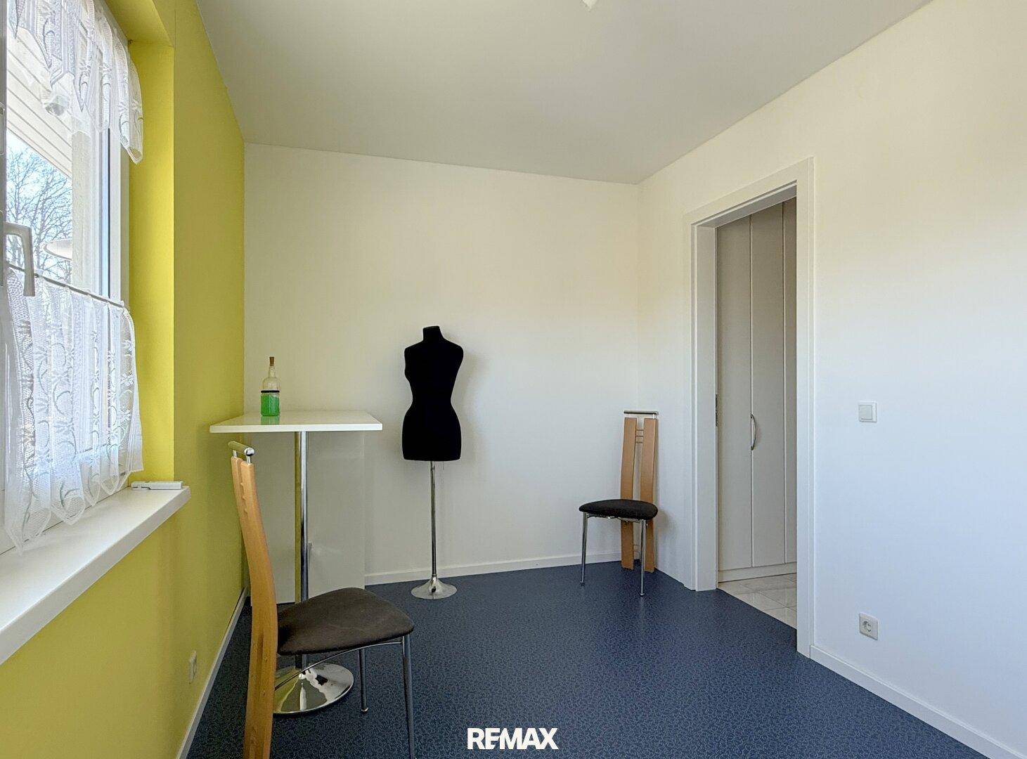 Einfaches Zimmer mit gelber Wand, Tisch und Stühlen, ideal als Gästezimmer.