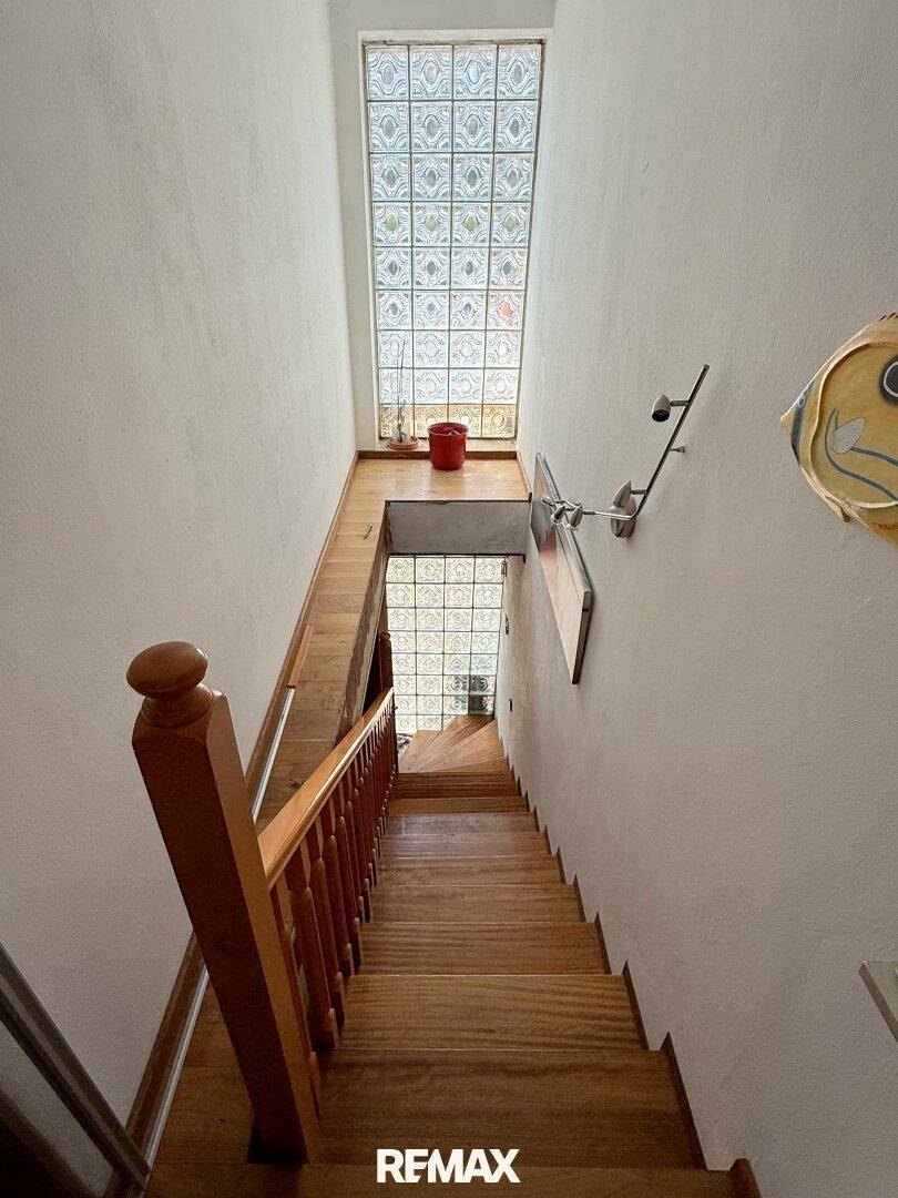 Treppenhaus mit Holzstufen und Glasbausteinfenstern, die für natürliches Licht sorgen.