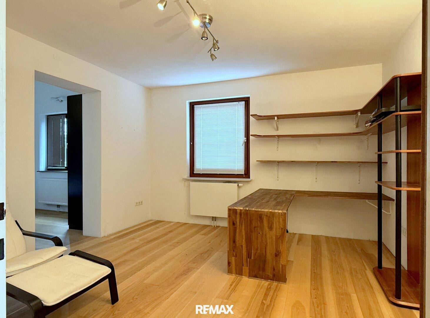 Helles Arbeitszimmer mit Holzboden, integriertem Schreibtisch und Regalen für Stauraum.