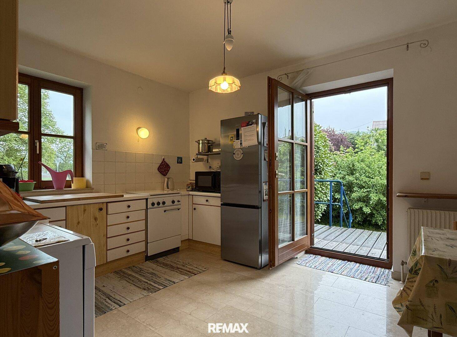 Helle Küche mit Zugang zu einer kleinen Terrasse und Blick in den Garten.