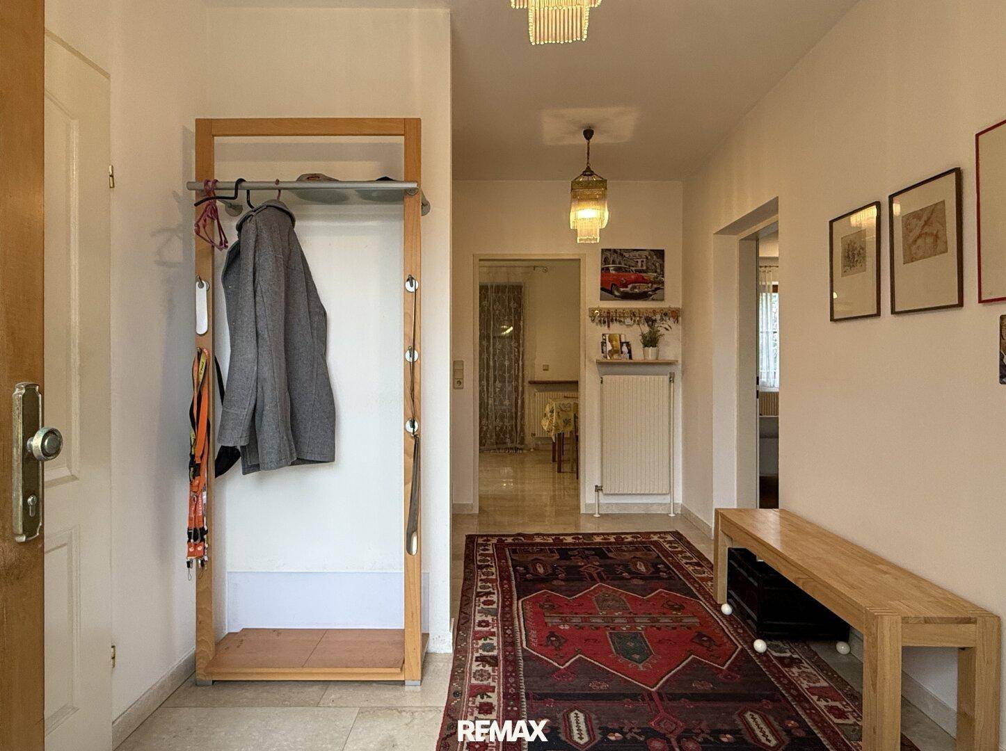 Eingangsbereich mit Garderobe, Teppich und hellem Fliesenboden.