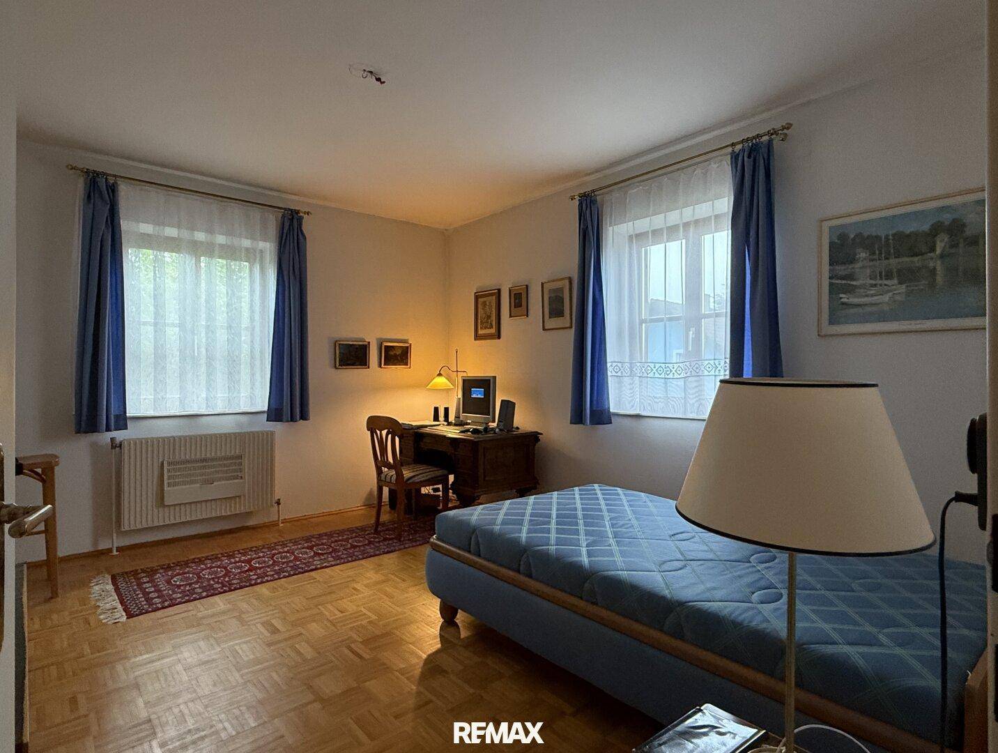 Schlafzimmer mit Parkettboden, Schreibtisch und einem Einzelbett.