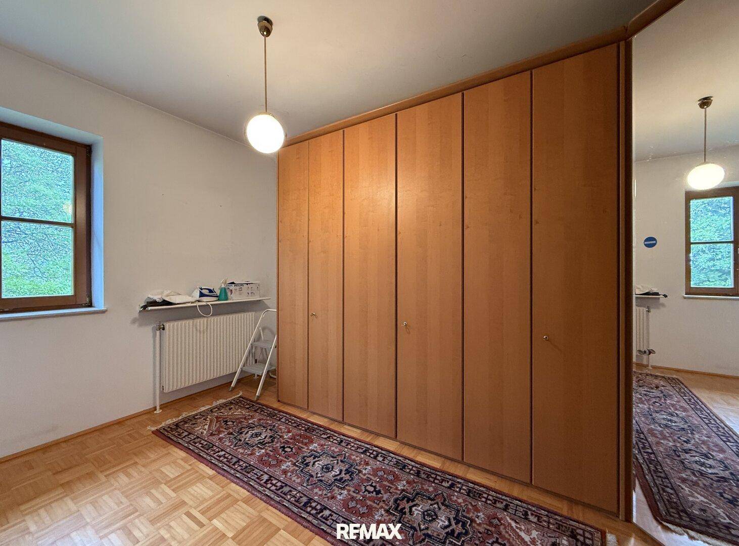 Schlafzimmer mit Parkettboden und einem großen Einbauschrank aus Holz.
