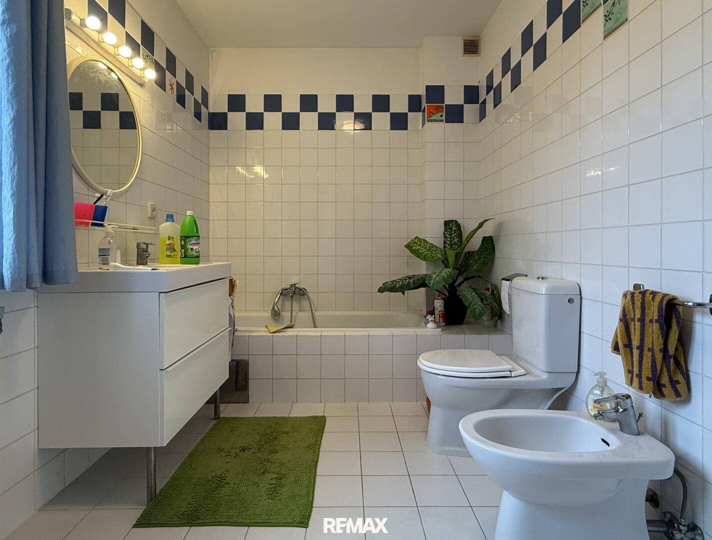 Badezimmer mit Badewanne, Bidet und weißen Fliesen mit blauen Akzenten.