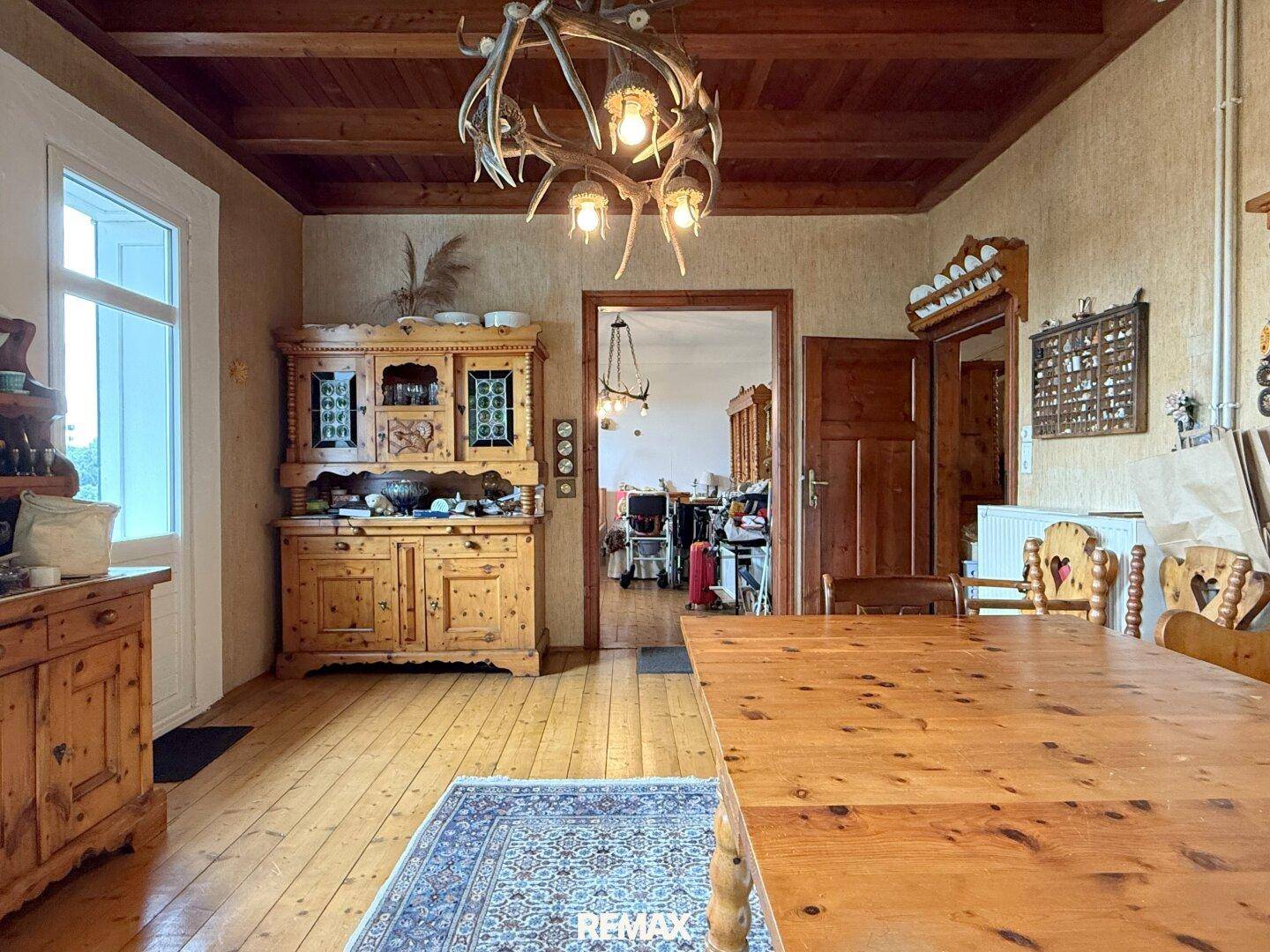 Traditioneller Essbereich mit Holzboden, Holzbalkendecke und einem Hirschgeweih-Kronleuchter.