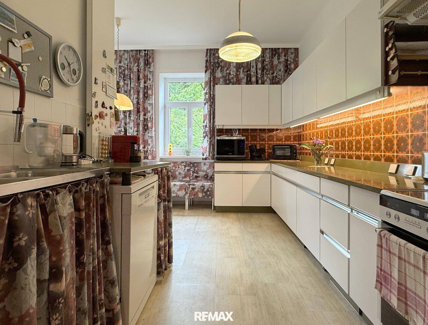 Funktionale Küche mit weißen Schränken, Fliesenrückwand und integriertem Geschirrspüler.