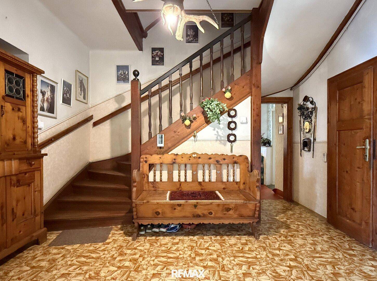 Geräumiger Eingangsbereich mit Holztreppe, traditionellen Möbeln und Fliesenboden.