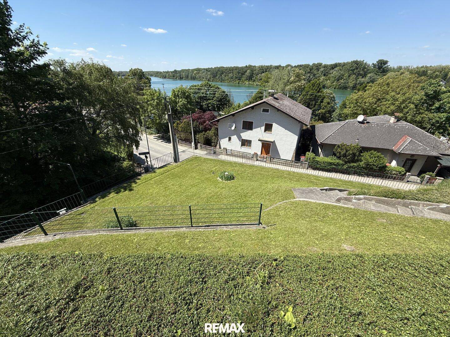 Garten mit Rasenfläche und weitem Blick auf den See und die umliegende Landschaft.