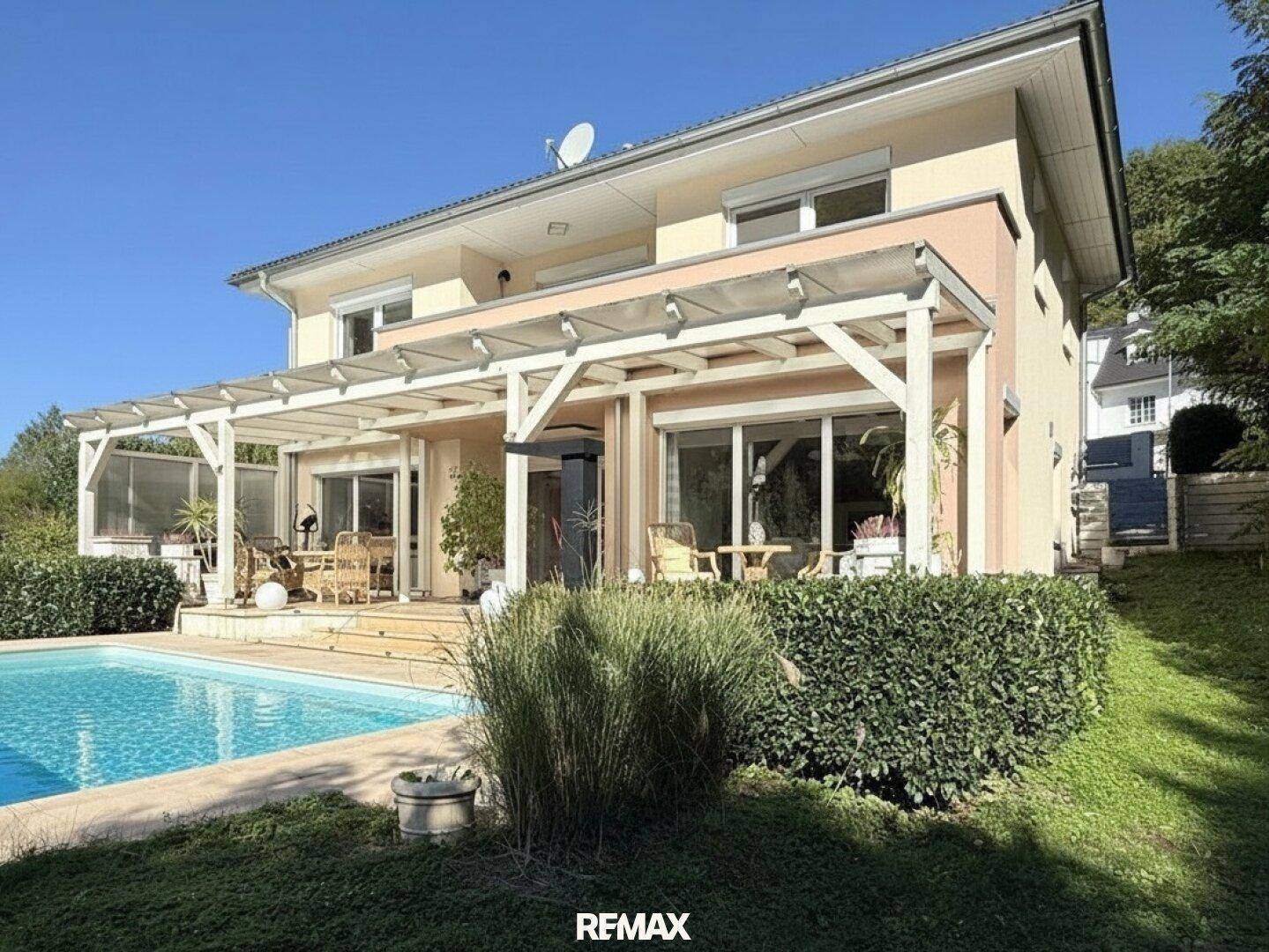 Rückansicht des Hauses mit Pool, Terrasse und gepflegtem Gartenbereich.