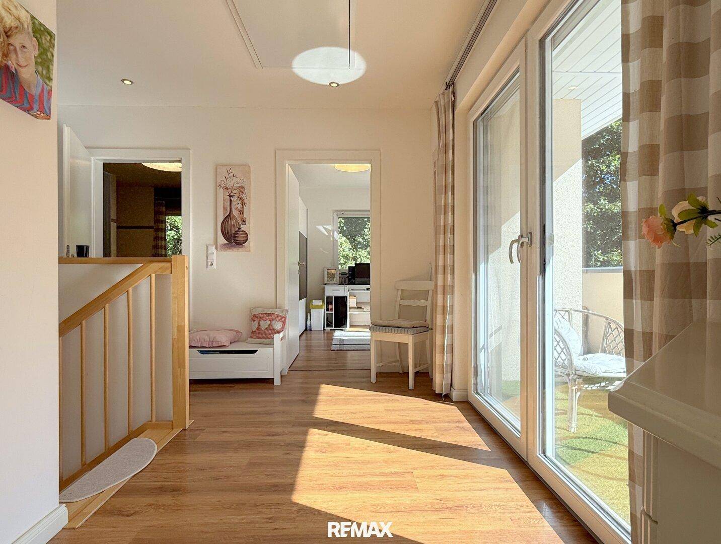 Heller Flur im Obergeschoss mit Zugang zu mehreren Räumen und Balkon.