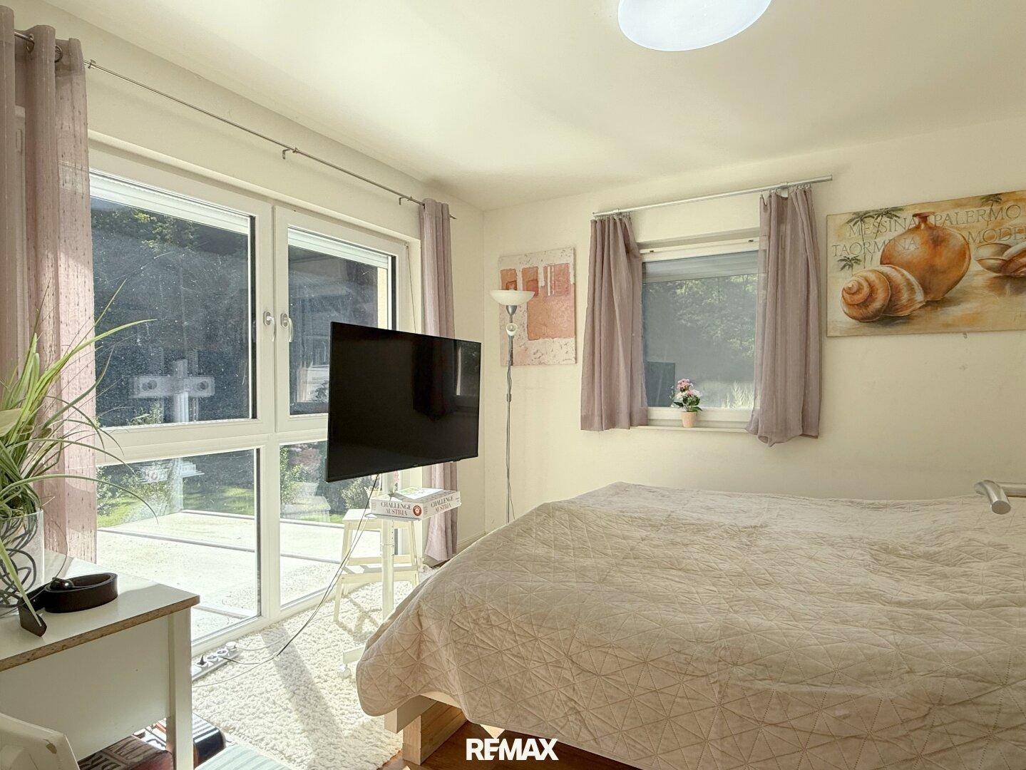 Schlafzimmer mit großem Bett, Holzboden und direktem Zugang zum Garten.