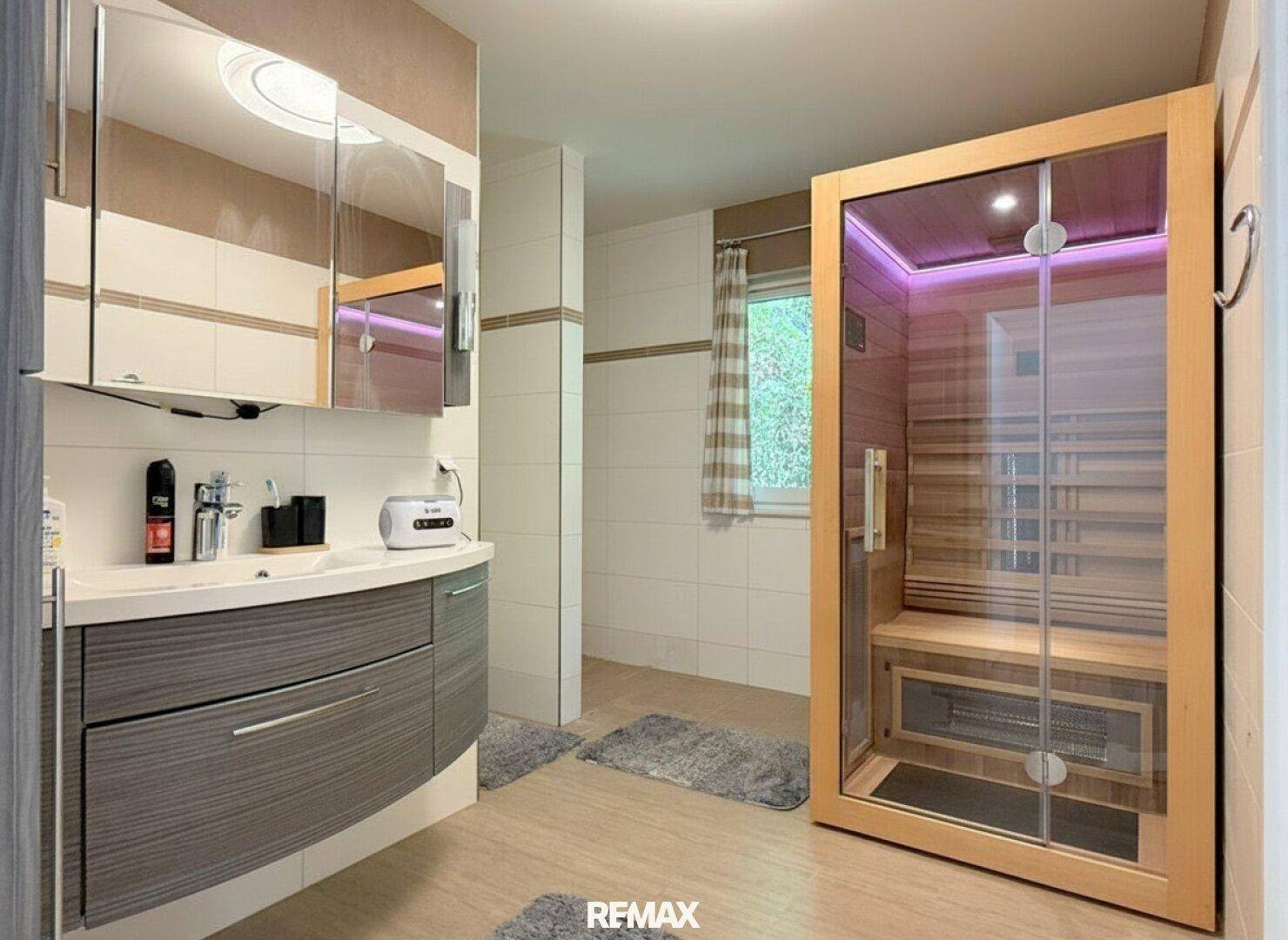 Modernes Badezimmer mit Waschtisch, Spiegelschrank und integrierter Sauna.