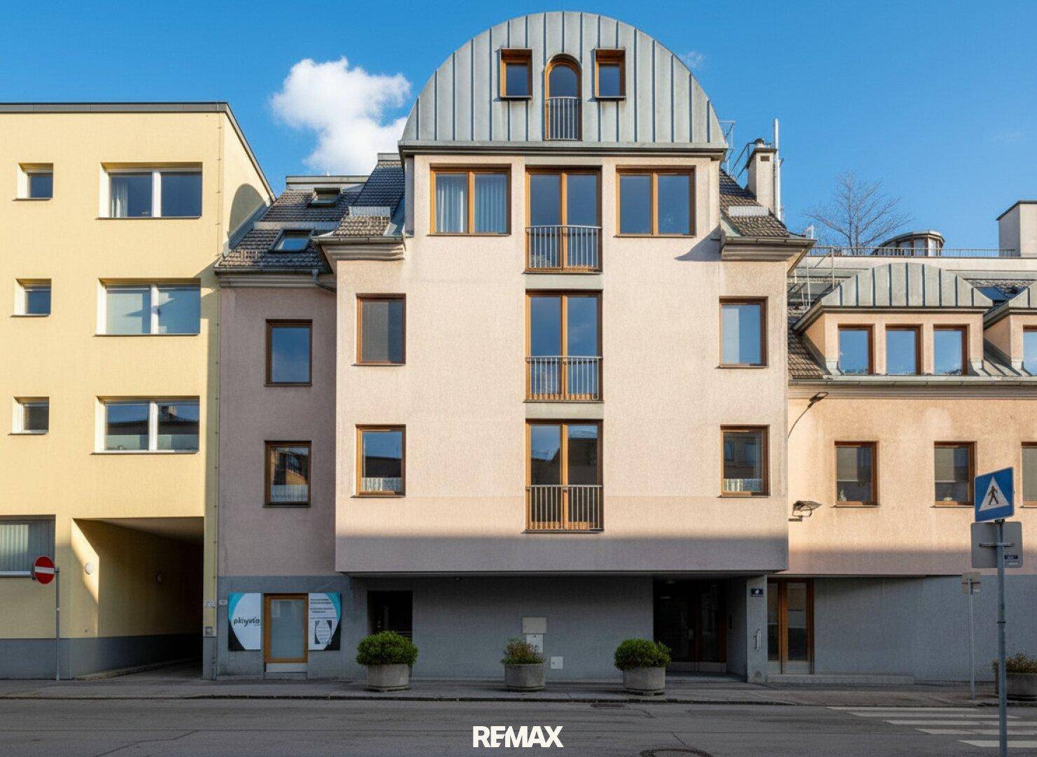 Attraktives Mehrfamilienhaus mit markanter Bogenfassade, vielen Fenstern und Balkonen in der Stadt.