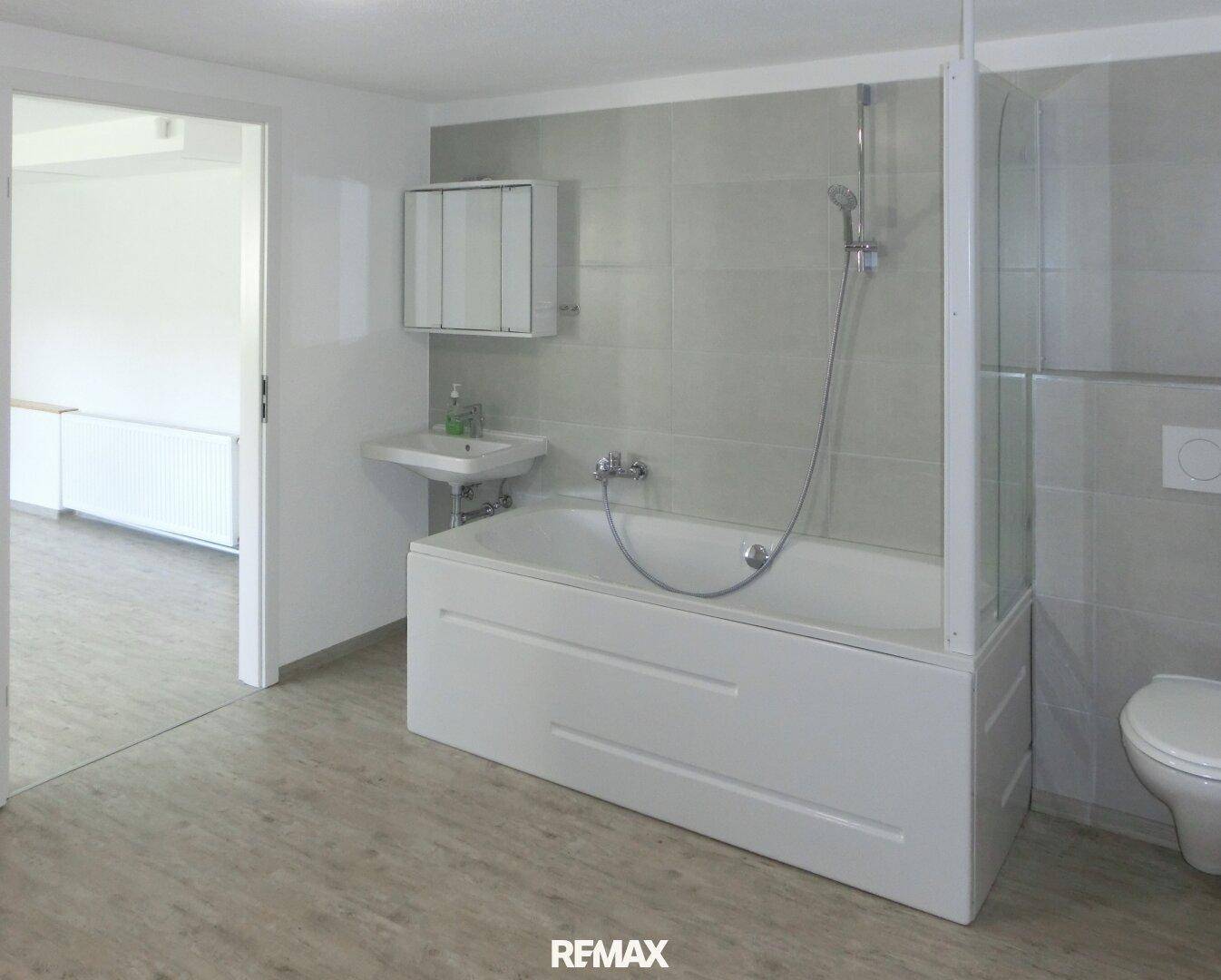 Funktionales Badezimmer mit Badewanne, integrierter Dusche und wandhängendem WC.