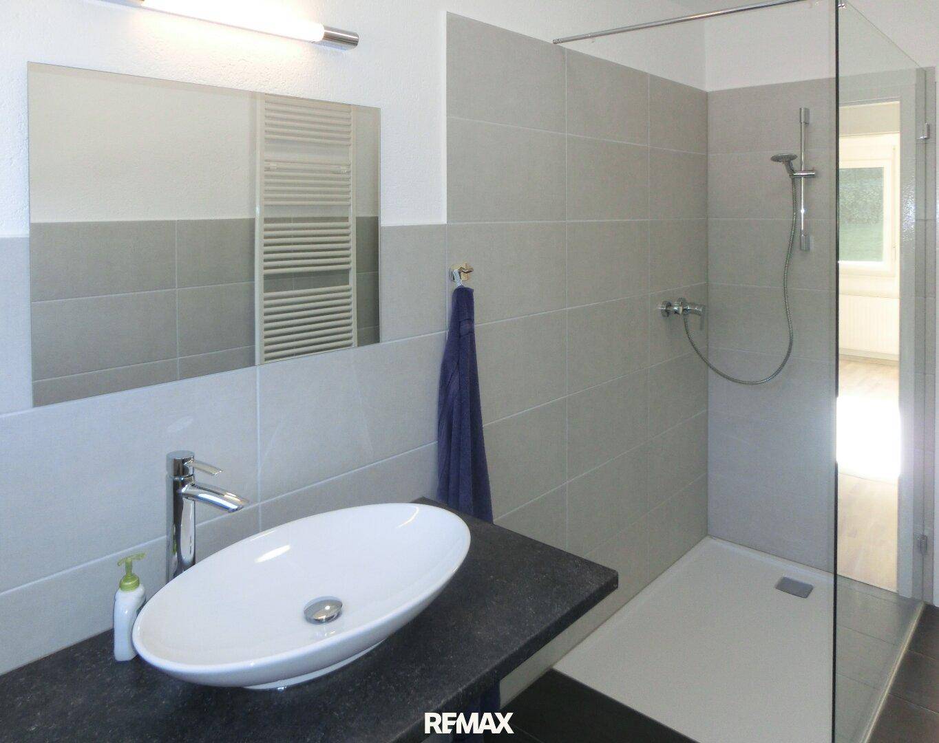 Modernes Badezimmer mit ebenerdiger Dusche, stilvollem Einzelwaschbecken und Handtuchheizkörper.