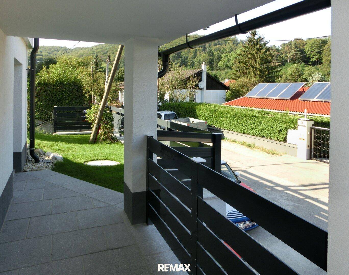 Überdachter Außenbereich oder Loggia mit Blick auf die grüne Umgebung und Solaranlagen.