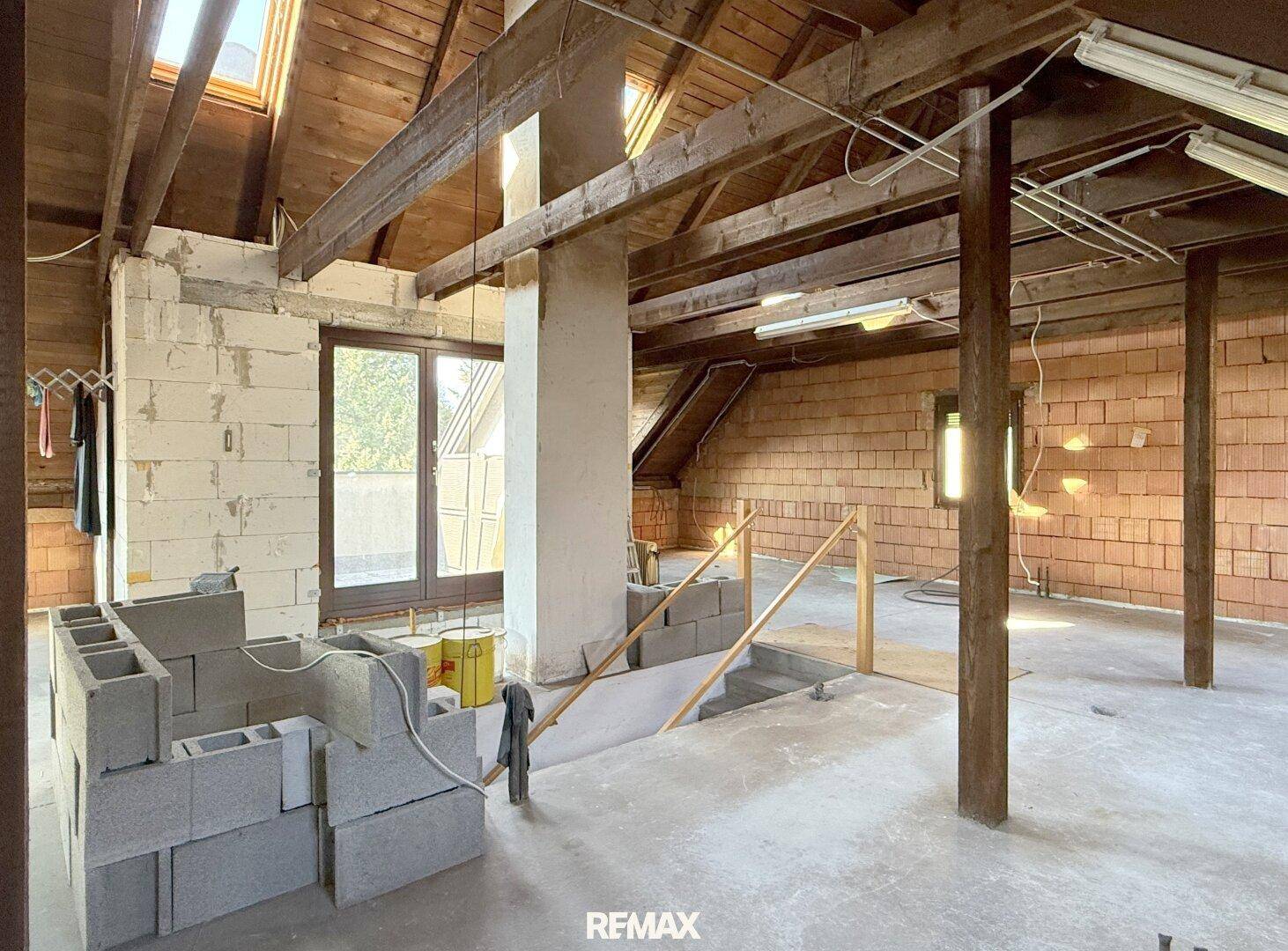 Geräumiger Dachboden im Rohbau mit Holzbalken und Fenstern, bereit zum Ausbau.