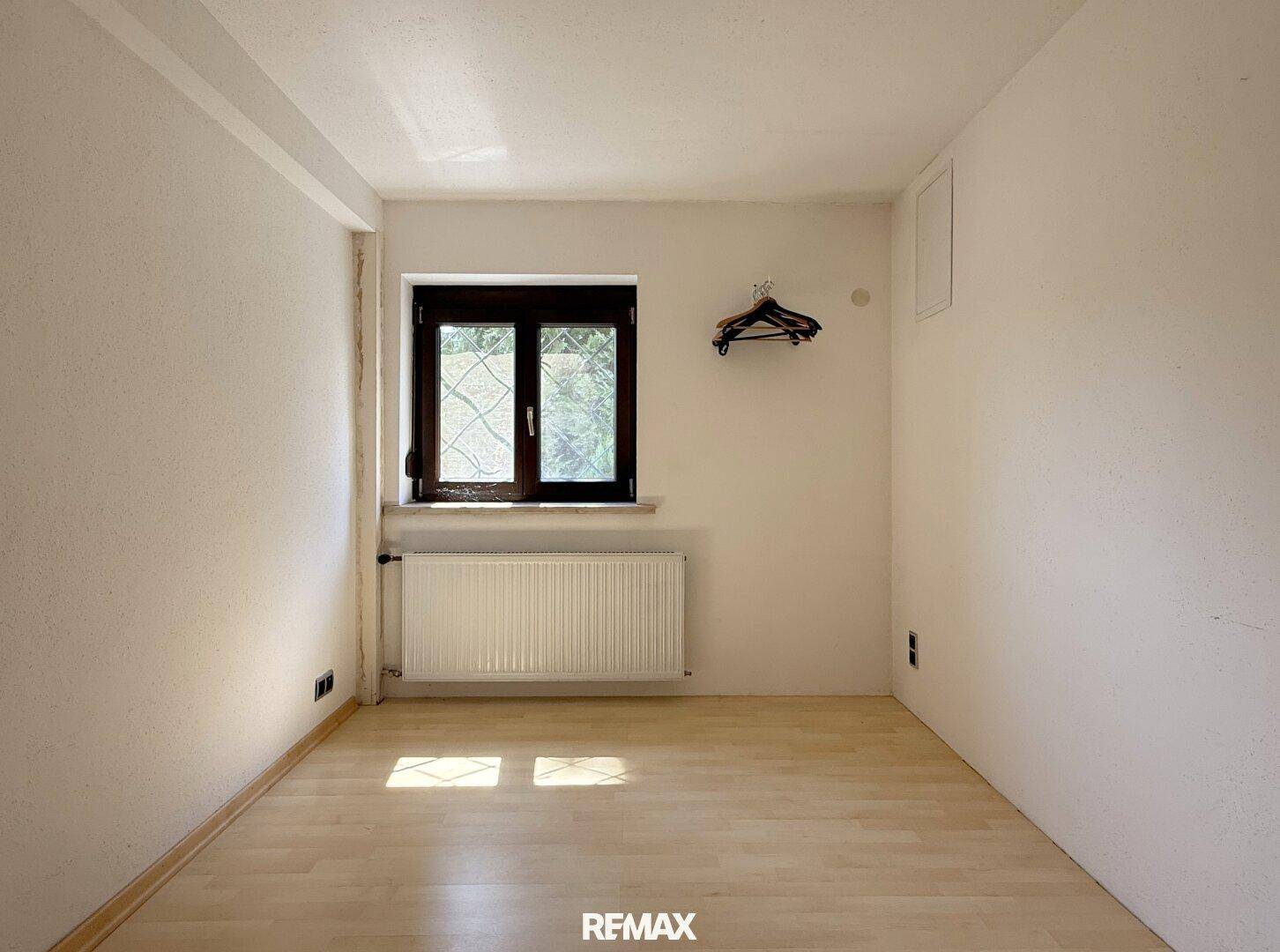Einfaches Schlafzimmer mit Laminatboden und Fenster, ideal für individuelle Gestaltung.