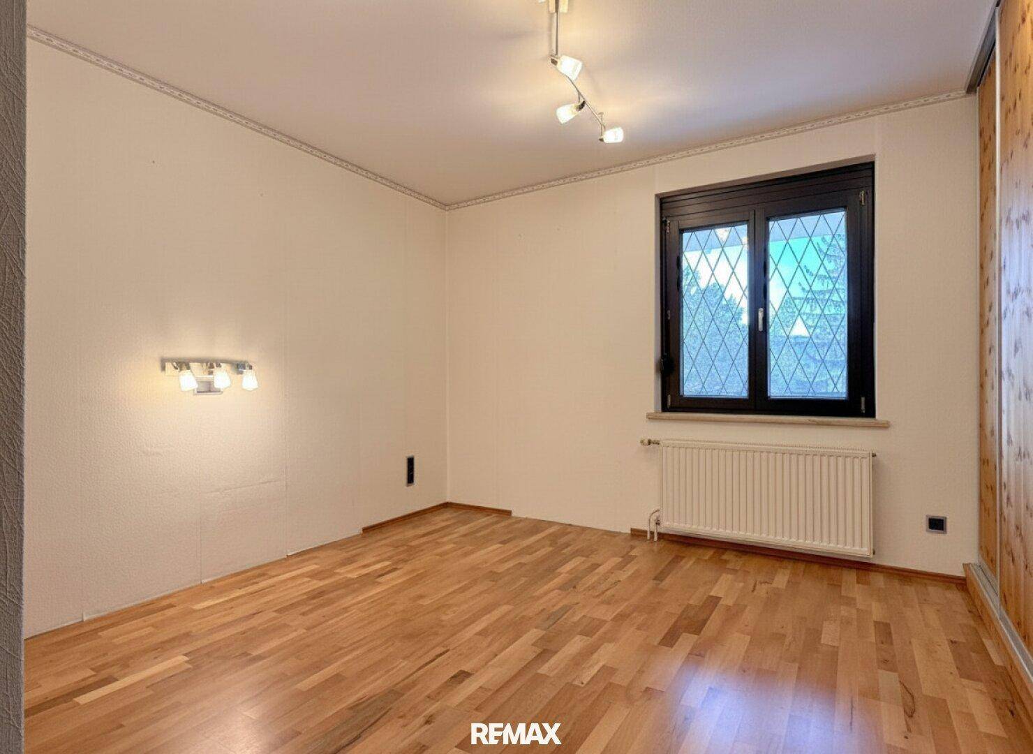 Helles Schlafzimmer mit Holzboden und Holzvertäfelung, bereit zur individuellen Gestaltung.