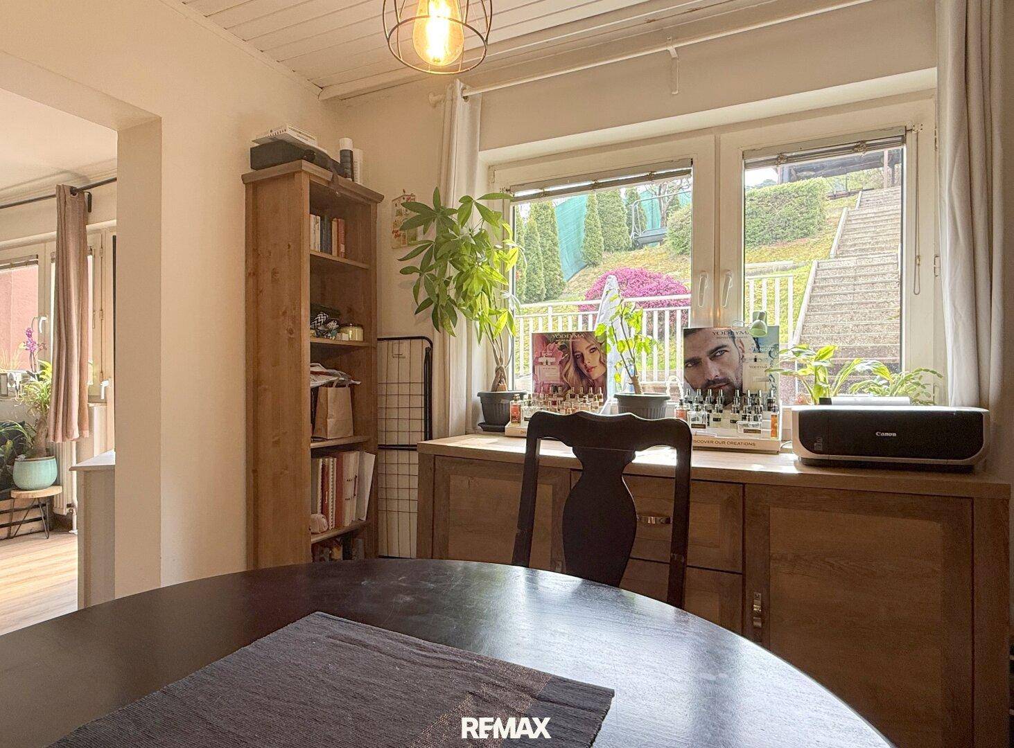 Essbereich mit Holztisch, Stühlen und Fenster mit Blick auf den gestuften Garten.