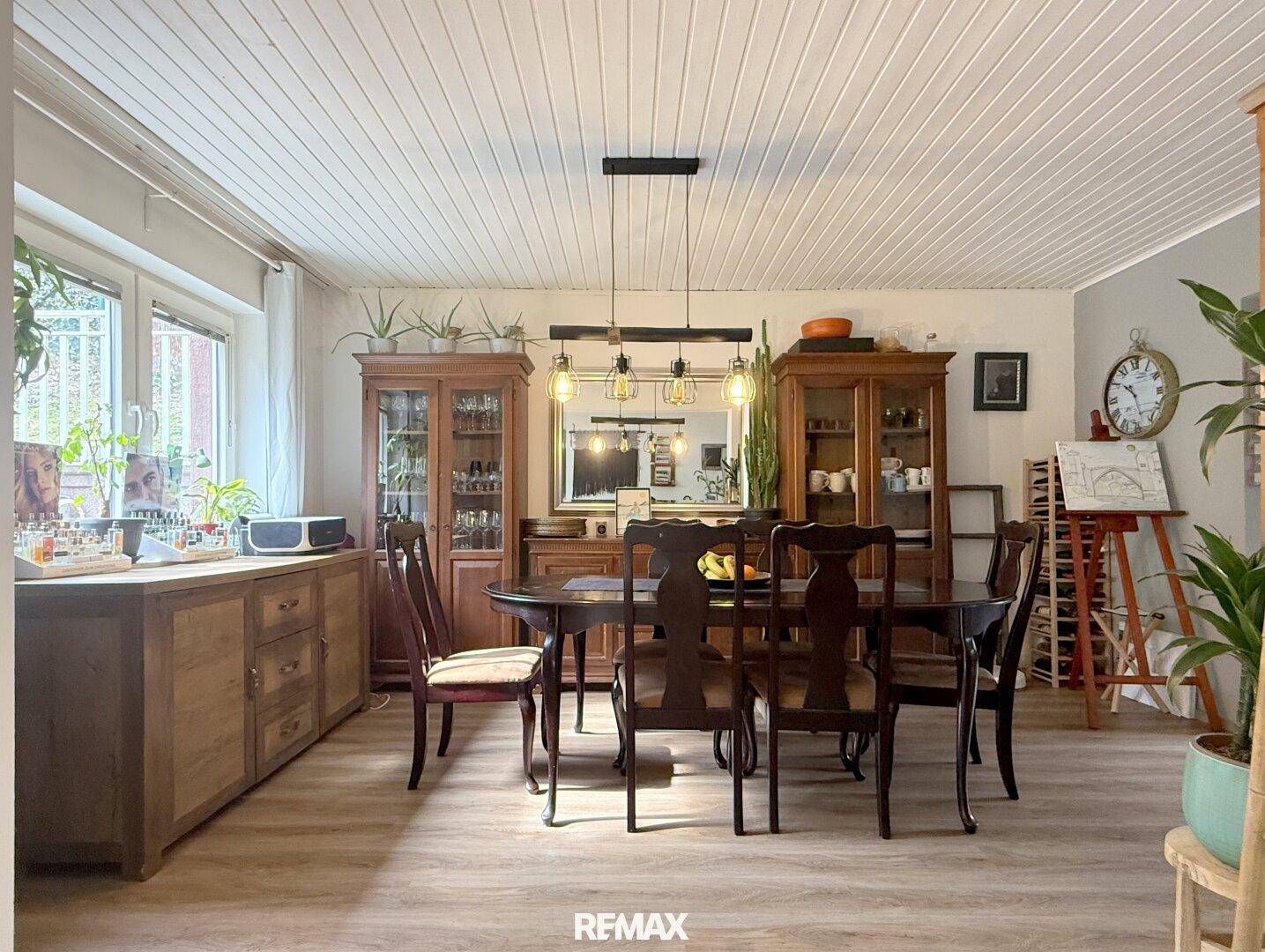 Traditioneller Essbereich mit großem Holztisch, passenden Stühlen und Holzdeckenverkleidung.