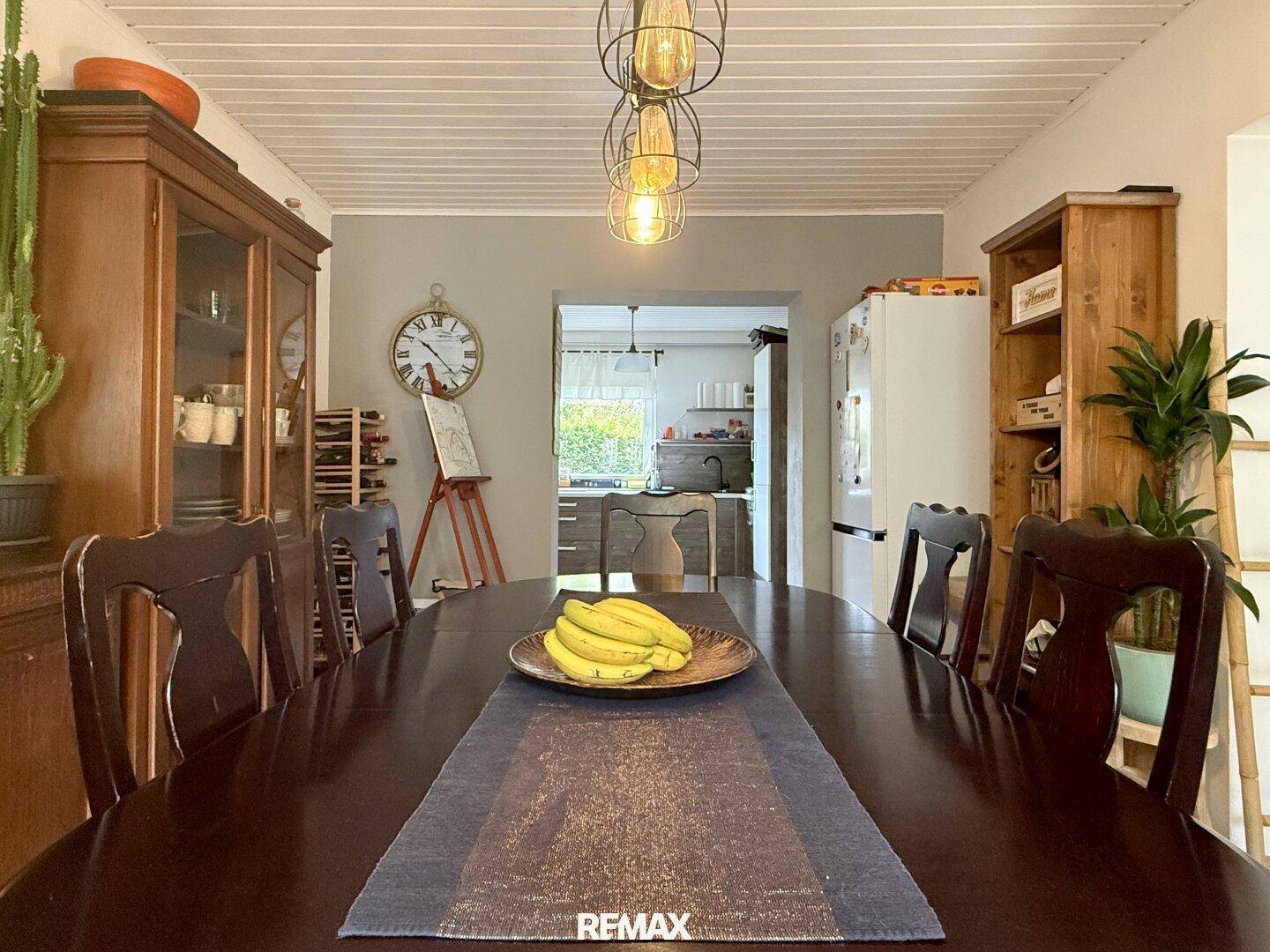 Esszimmer mit großem Holztisch und Blick in die angrenzende Küche.