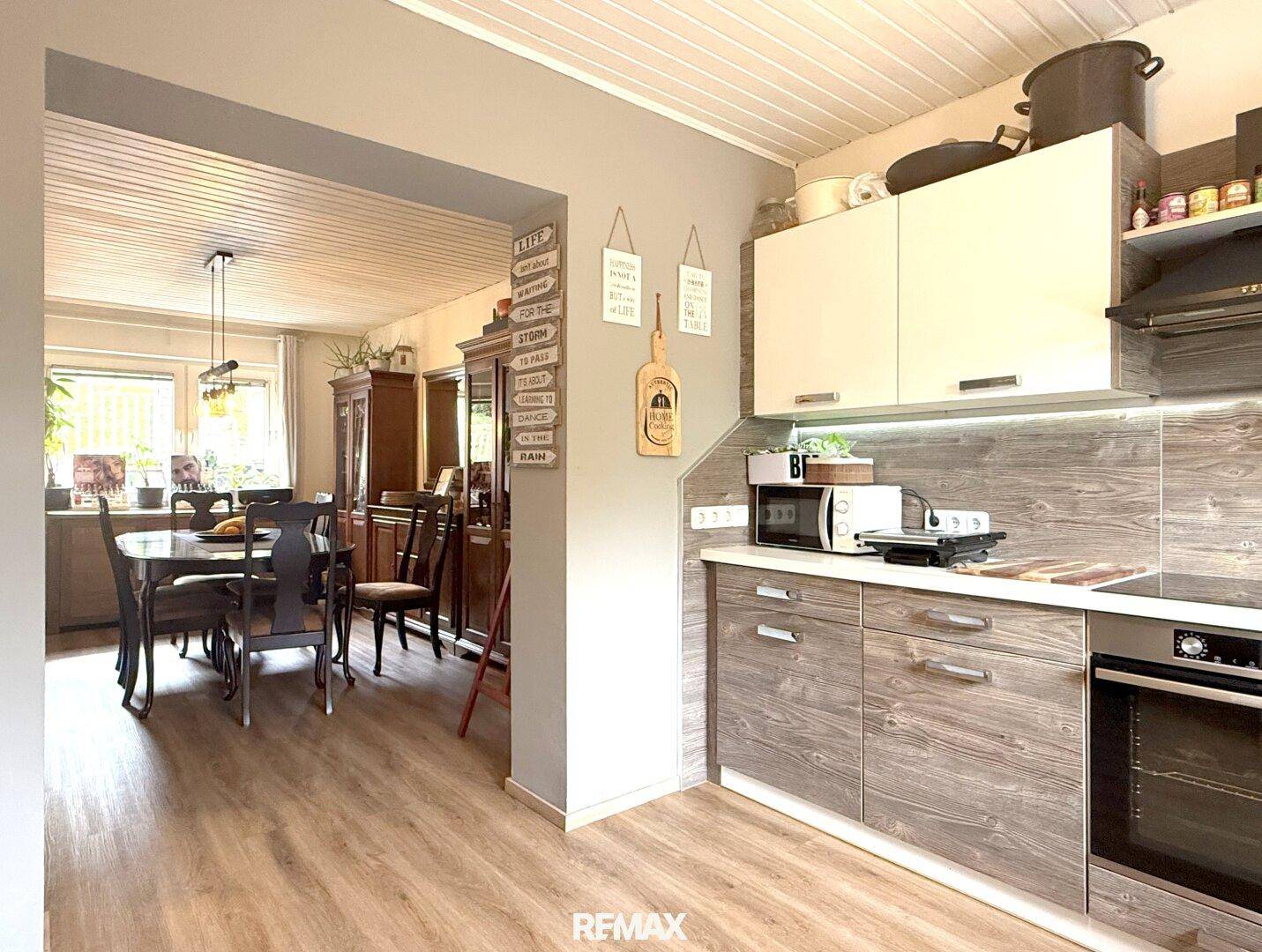 Moderne Küche mit Holzfronten, integrierten Geräten und offenem Übergang zum Essbereich.