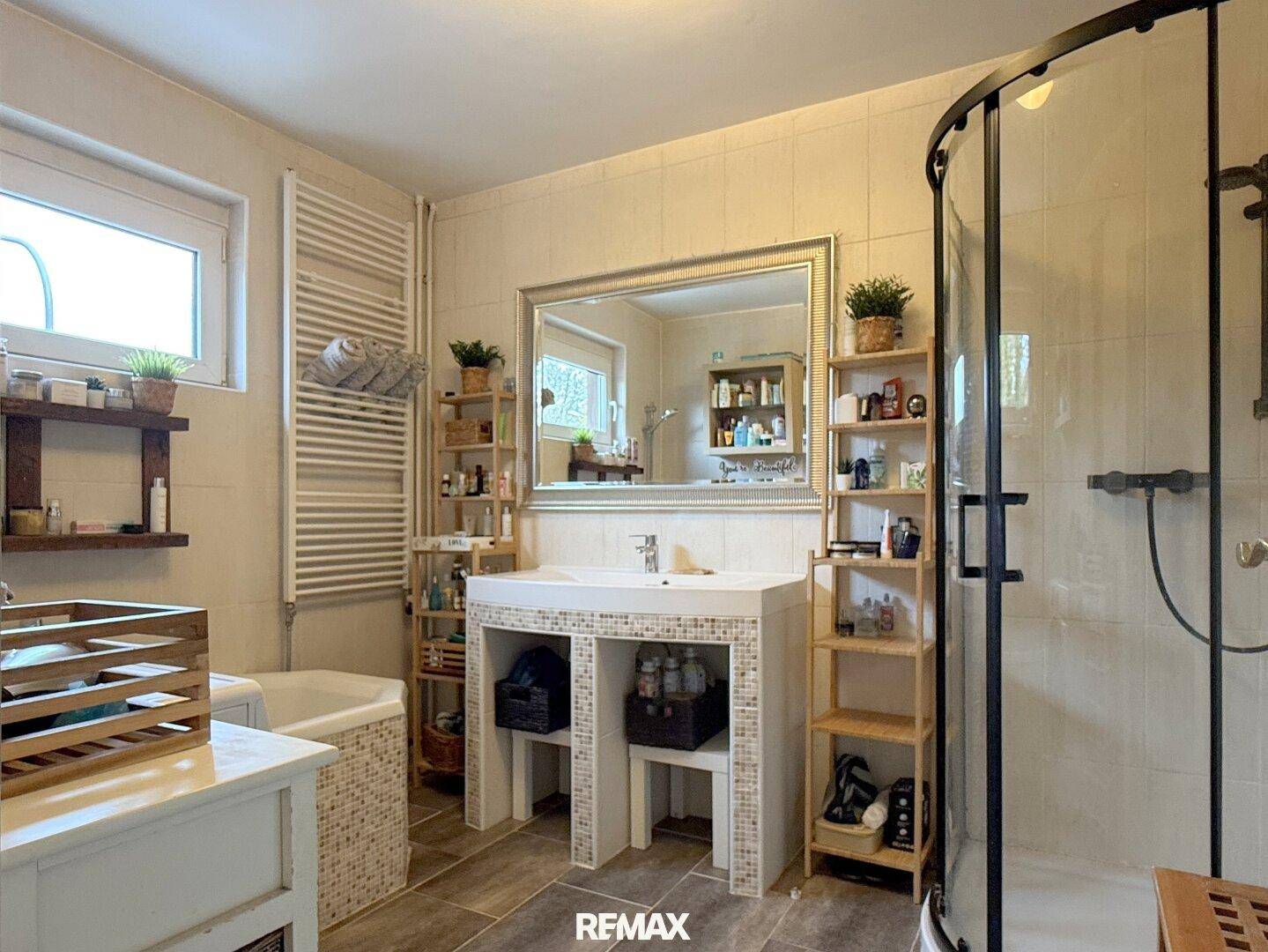 Helles Badezimmer mit Dusche, Badewanne, Einzelwaschbecken und beheiztem Handtuchhalter.