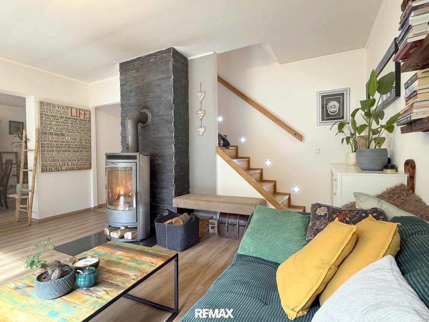 Gemütliches Wohnzimmer mit Kaminofen, Laminatboden und Treppe zum Obergeschoss.