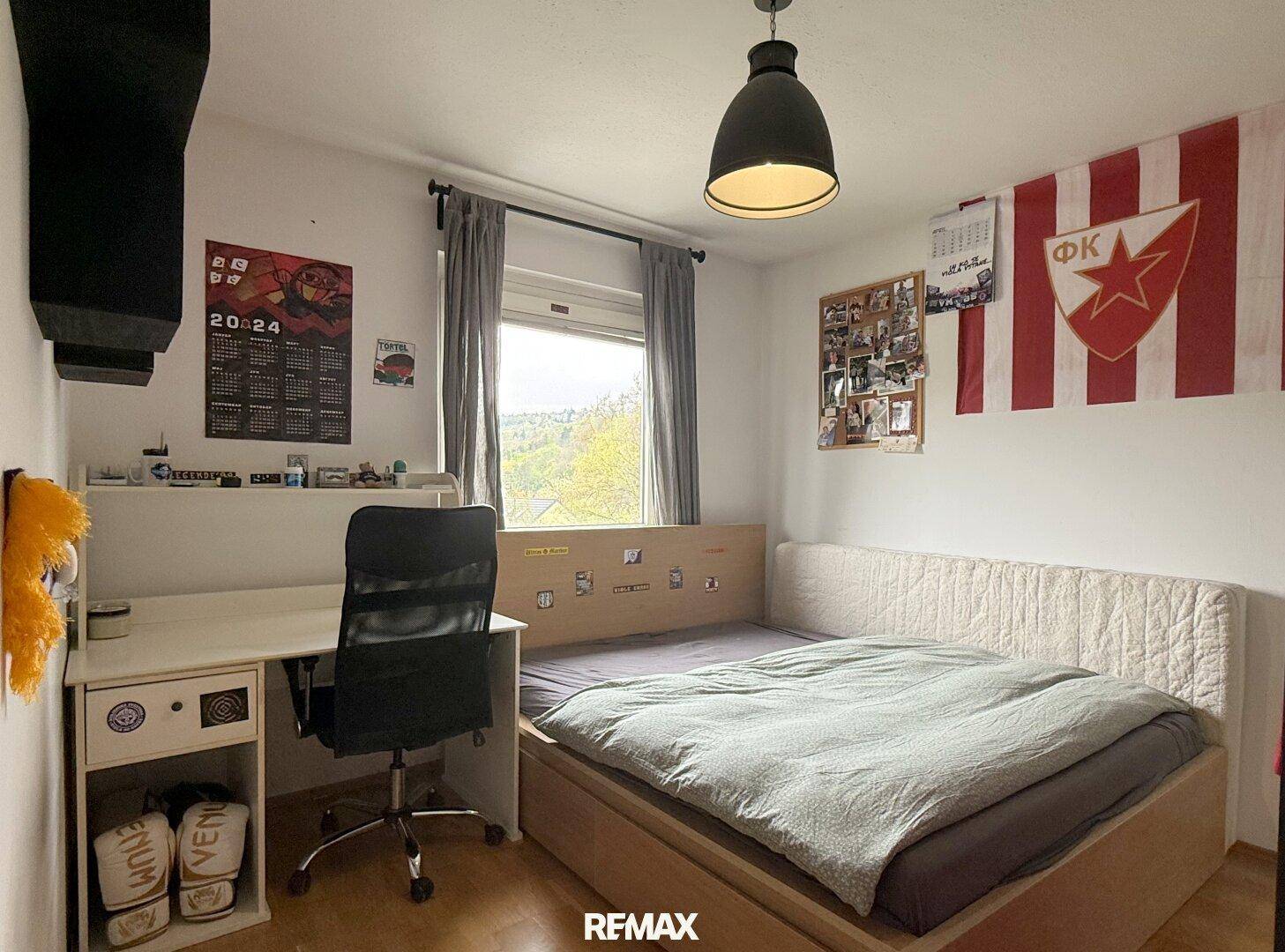 Jugendzimmer mit Bett, Schreibtisch und Fenster mit Ausblick.