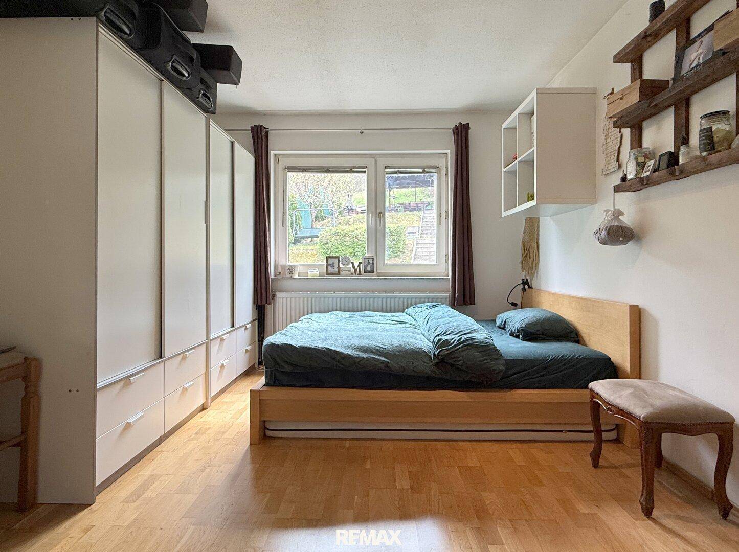 Schlafzimmer mit großem Kleiderschrank, Holzbett und Parkettboden.