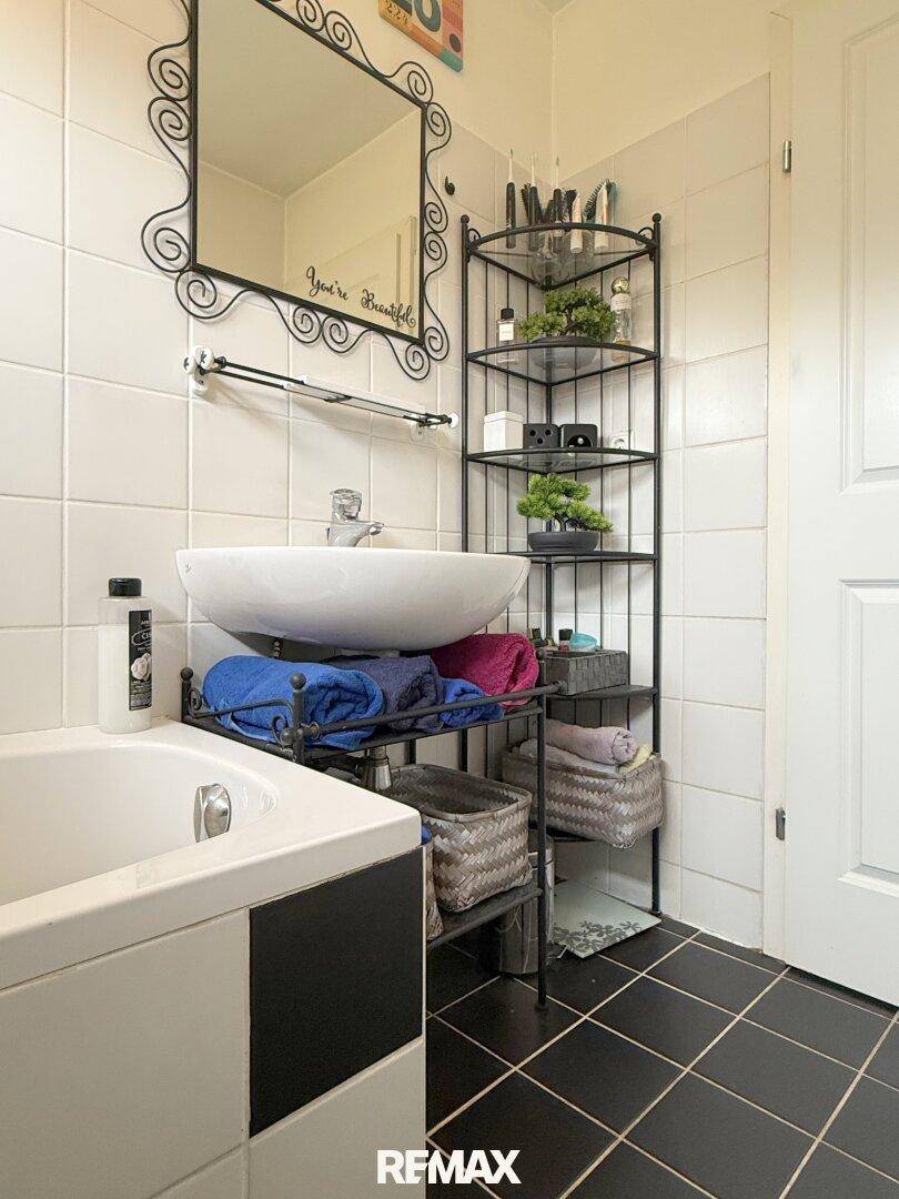Badezimmer mit Badewanne, modernem Waschbecken und dekorativem Spiegel.