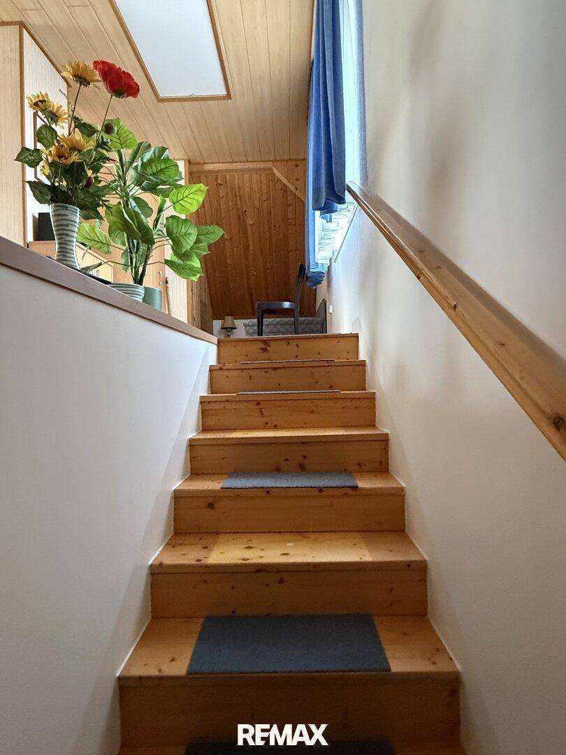 Holztreppe führt in das obere Stockwerk, mit natürlichem Lichteinfall von oben.