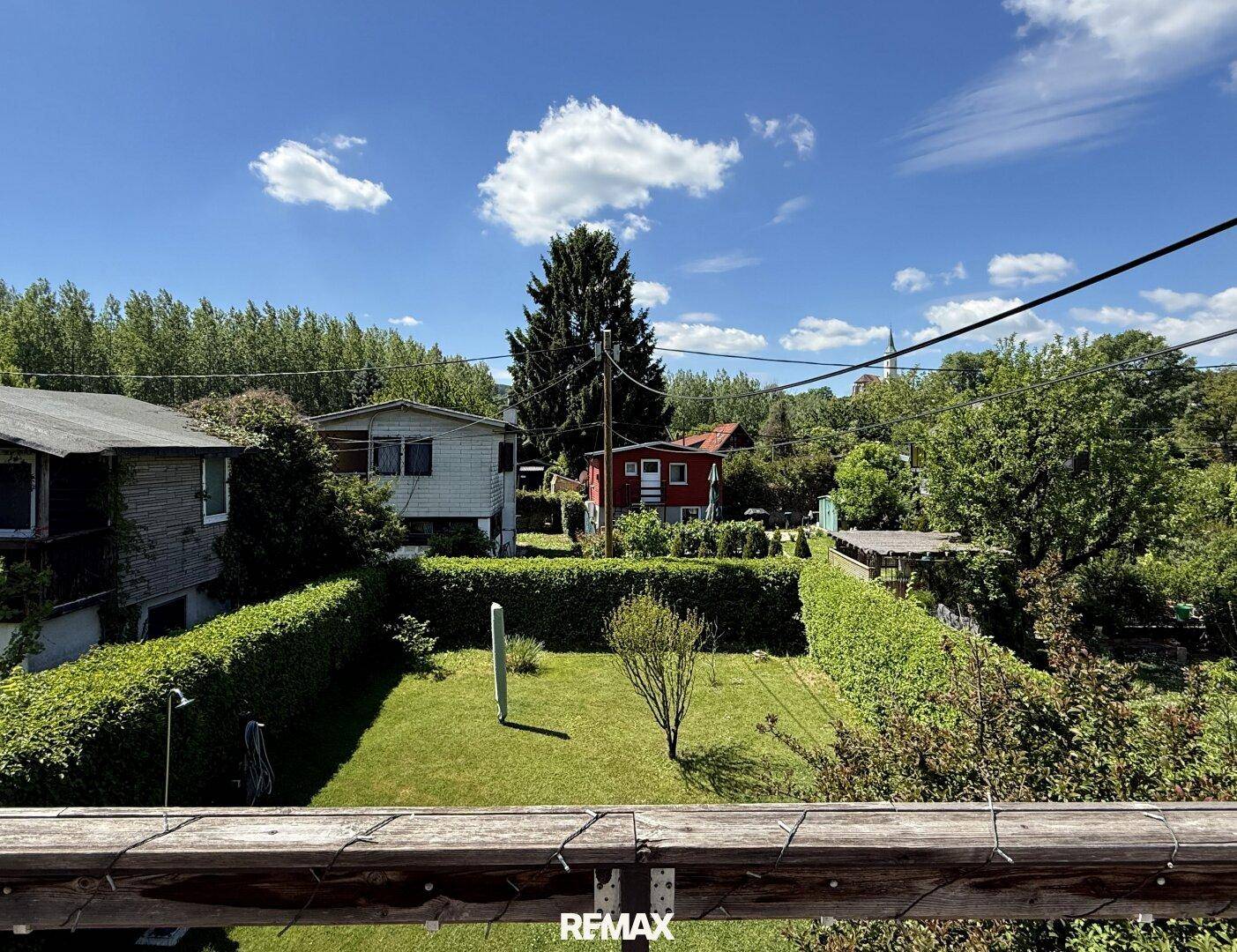 Weitläufiger Blick vom Balkon über den gepflegten Garten und die umliegende Landschaft.