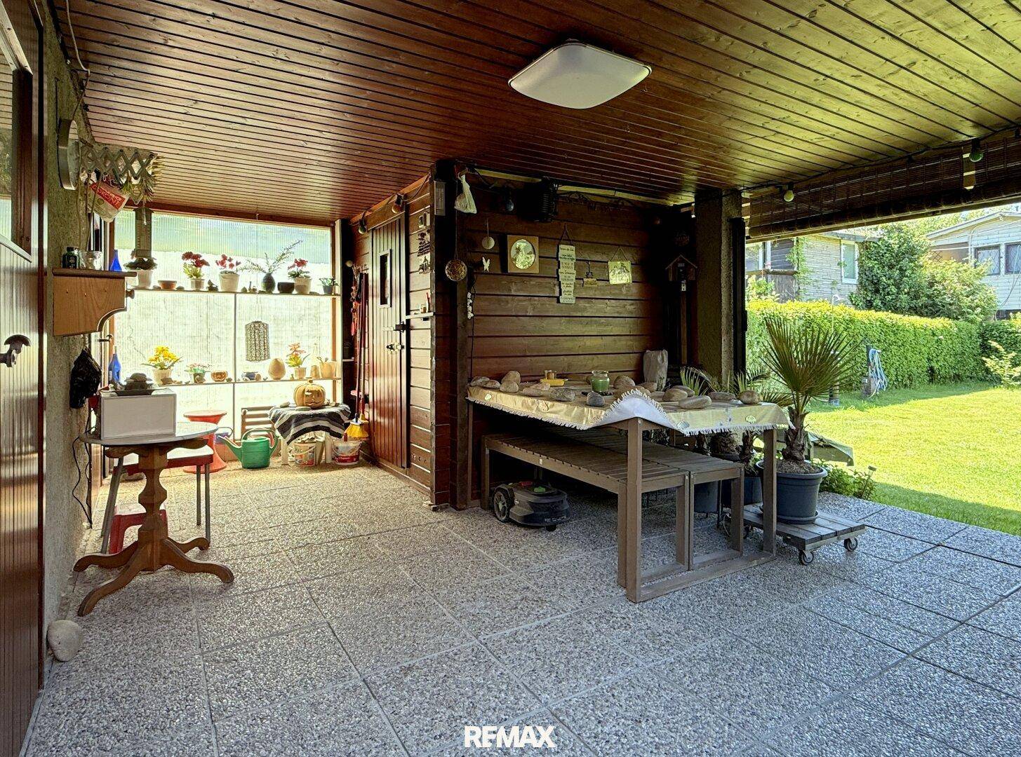 Überdachte Terrasse mit Fliesenboden und Holzwänden, ideal für entspannte Stunden im Freien.
