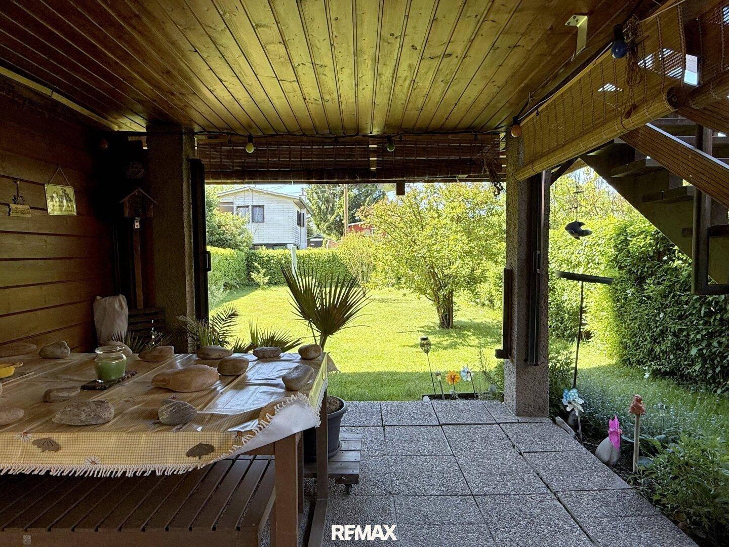 Gemütliche überdachte Terrasse mit Blick auf den grünen Garten und viel Tageslicht.