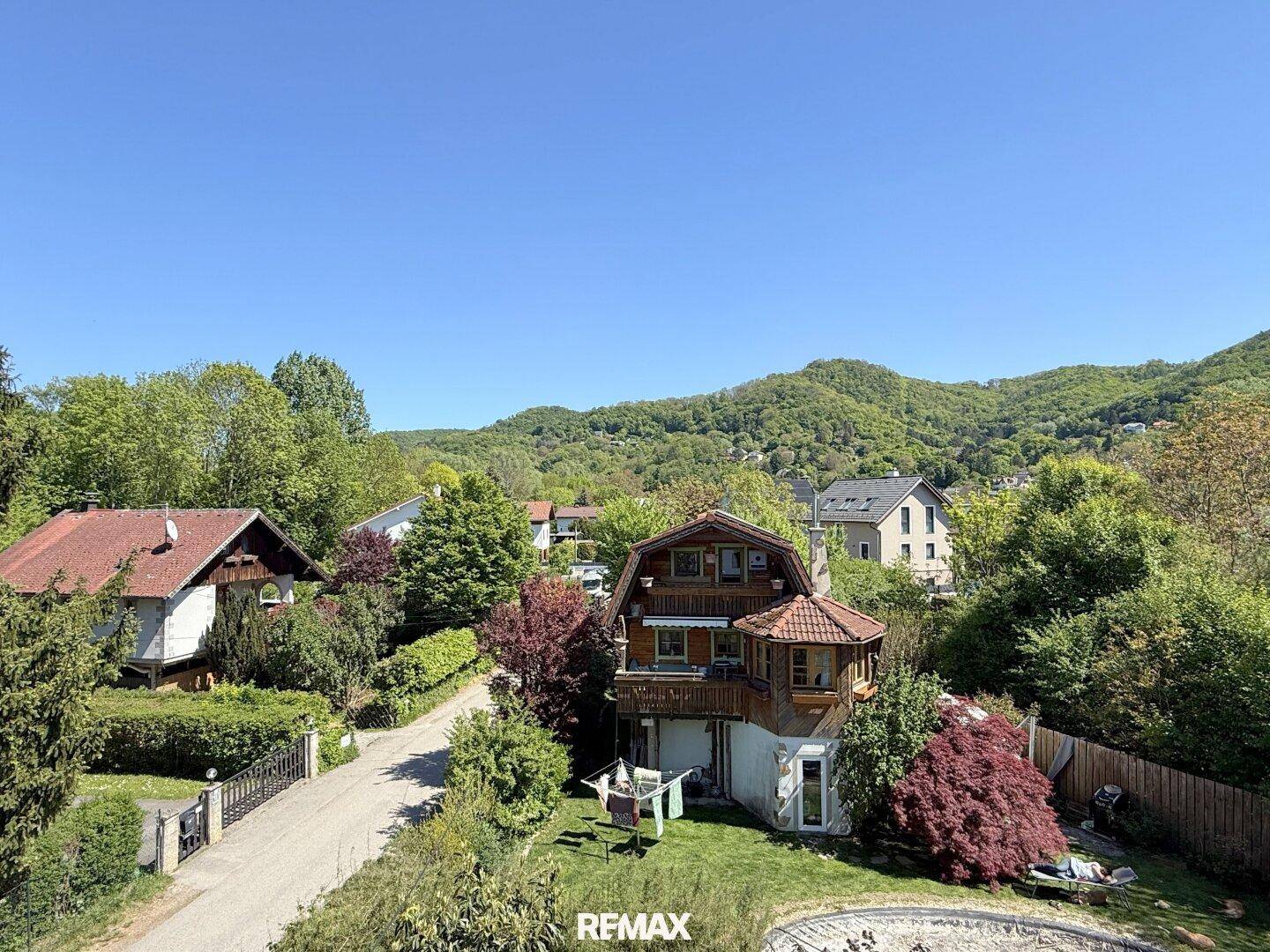Weitläufiger Blick auf das Haus und die umliegende grüne Hügellandschaft unter blauem Himmel.