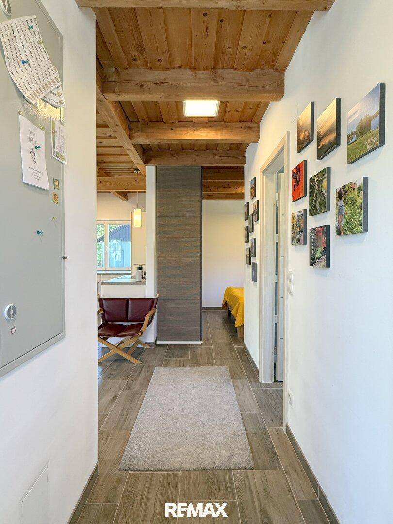 Heller Flur mit Holzbalkendecke, Fliesenboden und Zugang zu verschiedenen Räumen.
